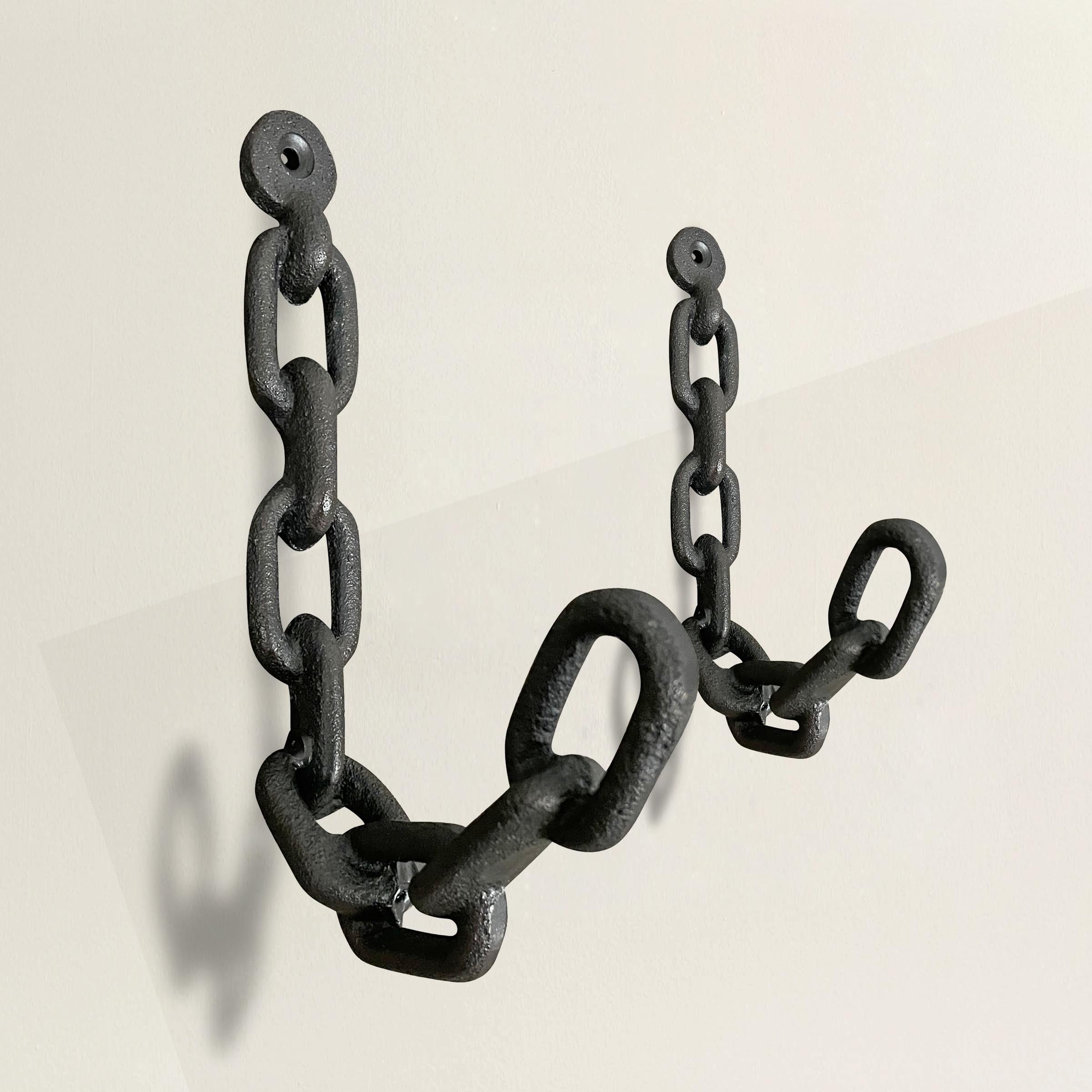 A striking pair of cast iron wall hooks designed to mimic chain links, and perfect for holding coats, hats, bags, dog leashes, or any myriad things you need to organize.