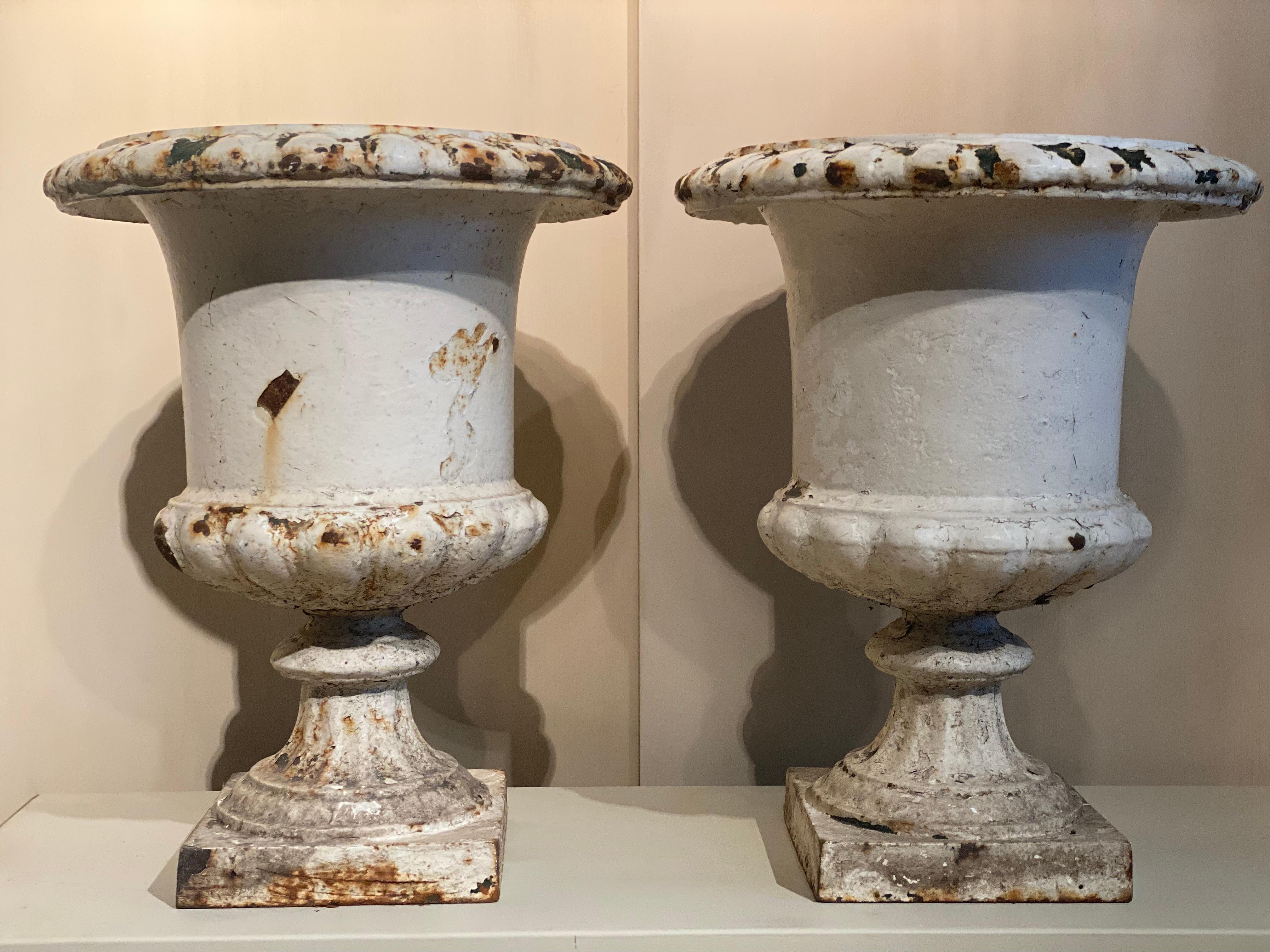 A nice pair of Cast Iron Garden urns, painted in a White- Cream Beige Color,
France from around the 1930 ies,
great patina and wear, some traces of rusting due to outside weather conditions,
classical Medici form,
to be used for different purposes,