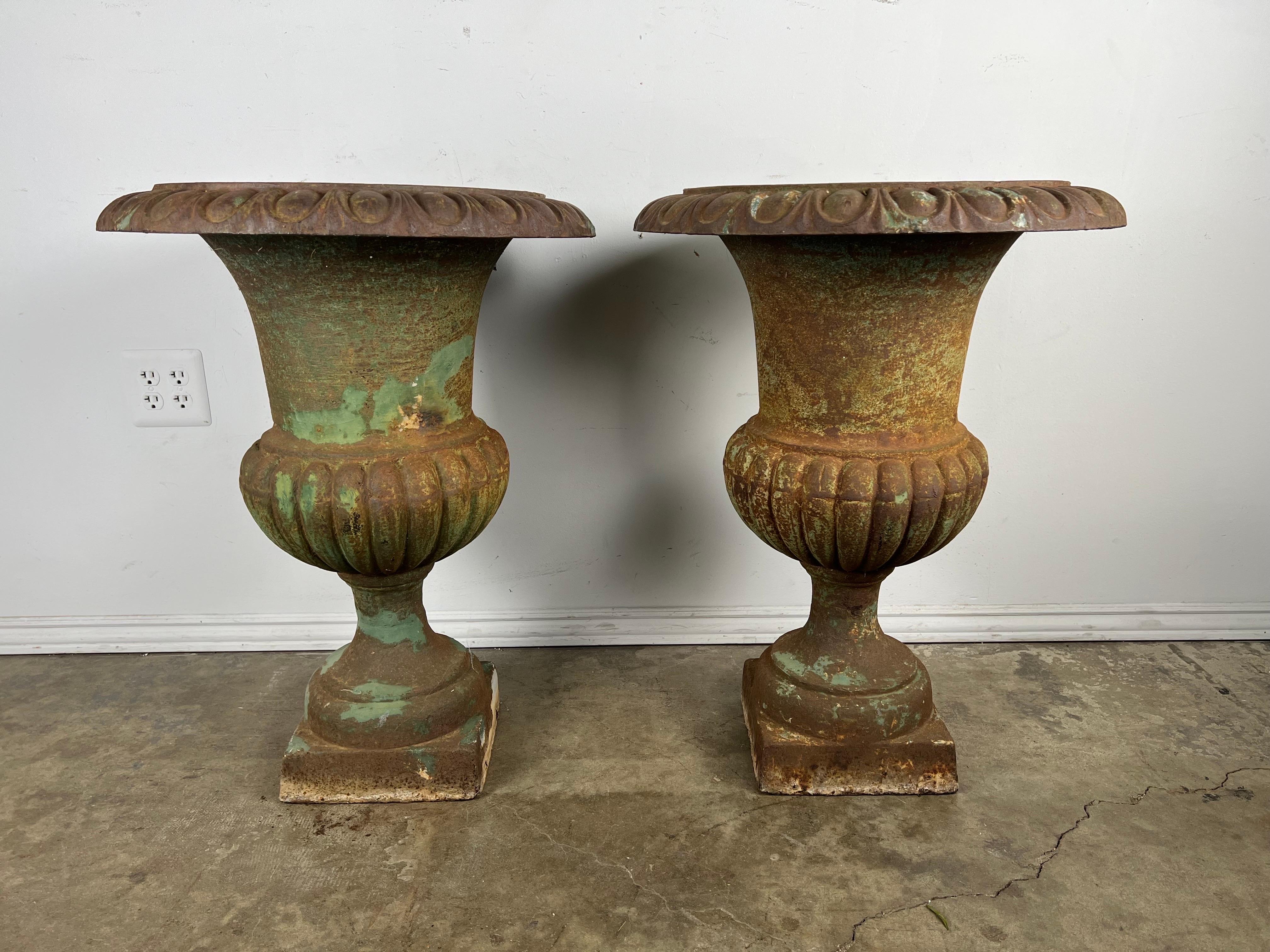 Pair of 19th century Italian cast iron urns. The urns have developed a beautiful patina over the years. They have rust but it adds charm to the antique planters.