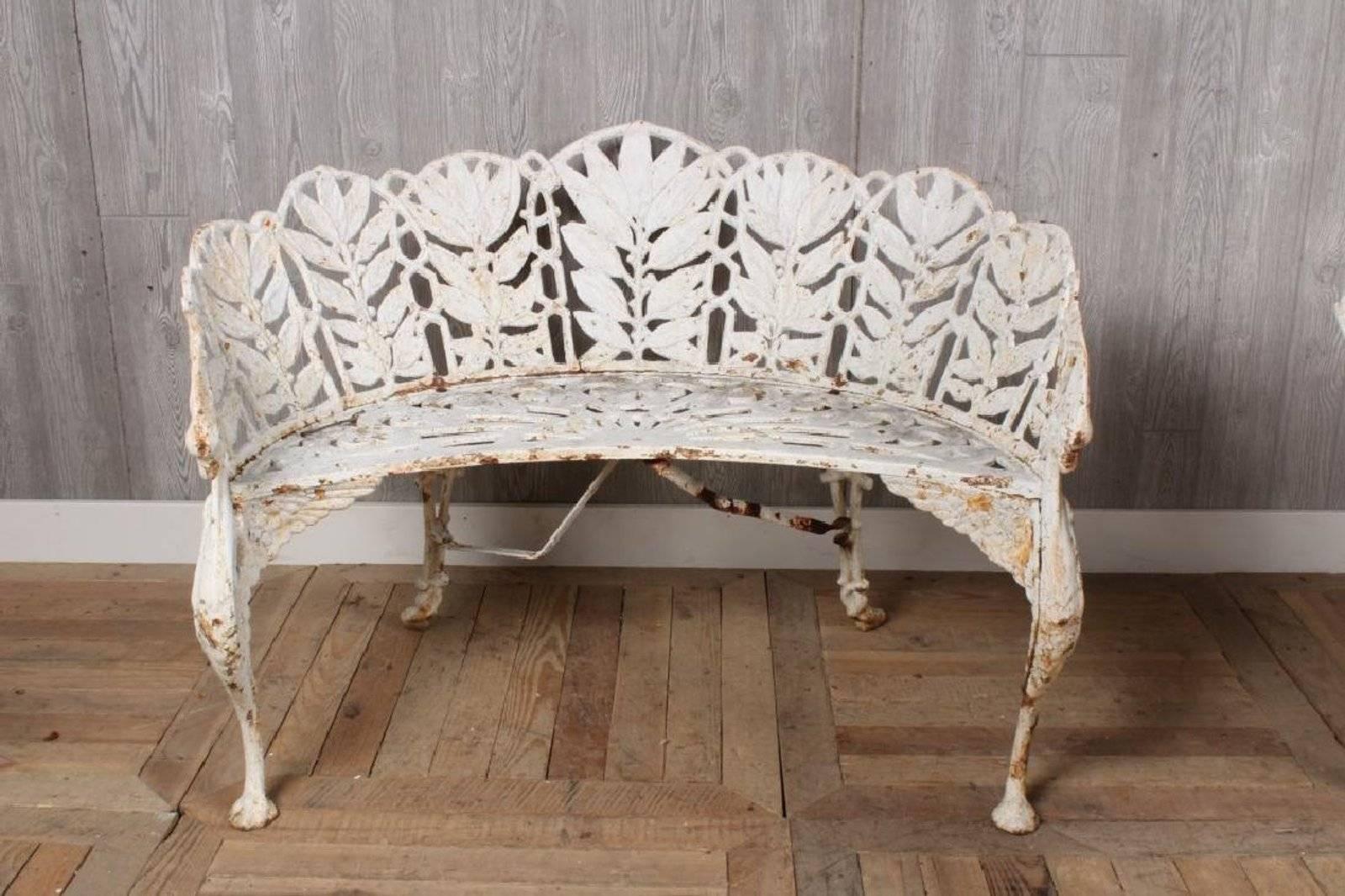 This is an exceptional pair of cast iron garden benches with beautiful painted patina. Laurel Pattern on backs and seats are lush and with defined griffin and cabriole legs.