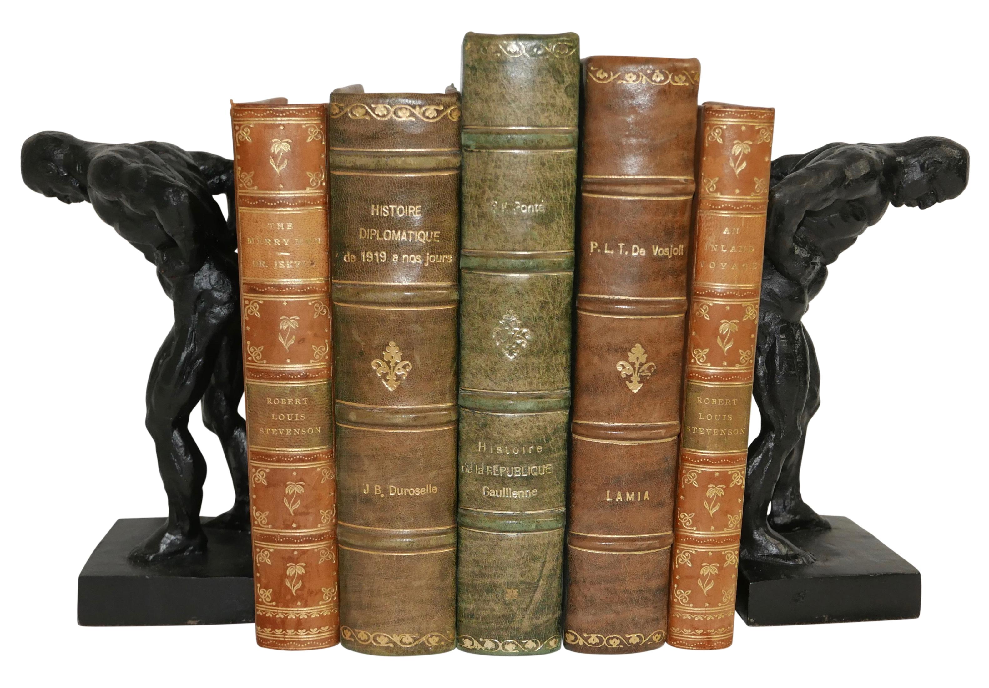 Muscular male figure bookends made of cast iron, standing on plinth bases.