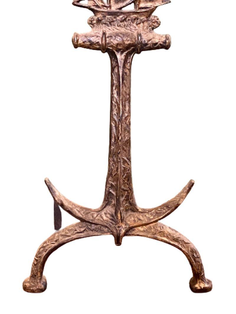 Antique Pair of Cast Iron Ship and Anchor Andirons, circa 1920, cast iron anchor with embossed surface, surmounted by a two-masted schooner under full sail on robust wave pediment, raised on domed legs, all in a nicely worn gilded finish. The log