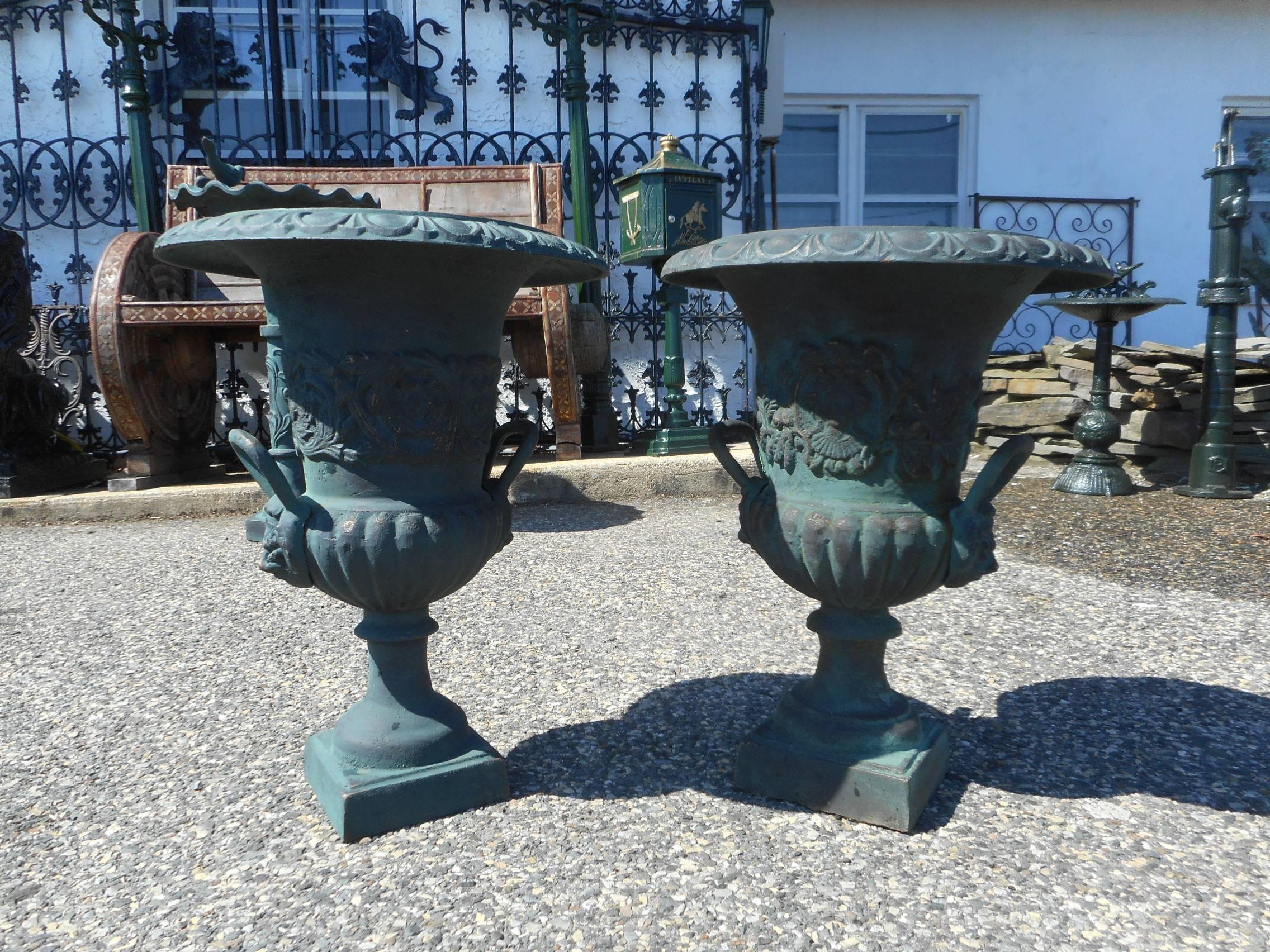 This beautiful pair of cast iron urns feature decorative handles on each side, etched designs, and a pedestal base. A large opening on top provides ample space to put plants or flowers inside for display. A gorgeous design that makes an impression