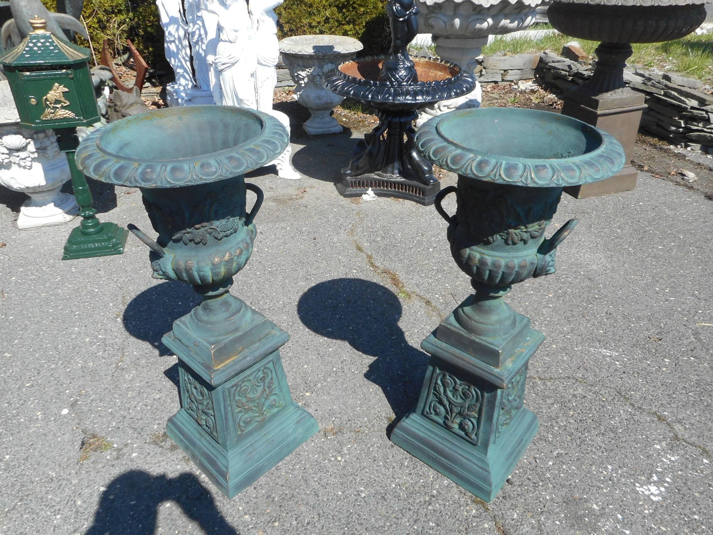 A gorgeous pair of cast iron urns that sit on top of a separate pedestal base. Excellent etched detail throughout, decorative handles, and a large opening on top make these urns perfect for any setting. Please confirm item location (NY or NJ).