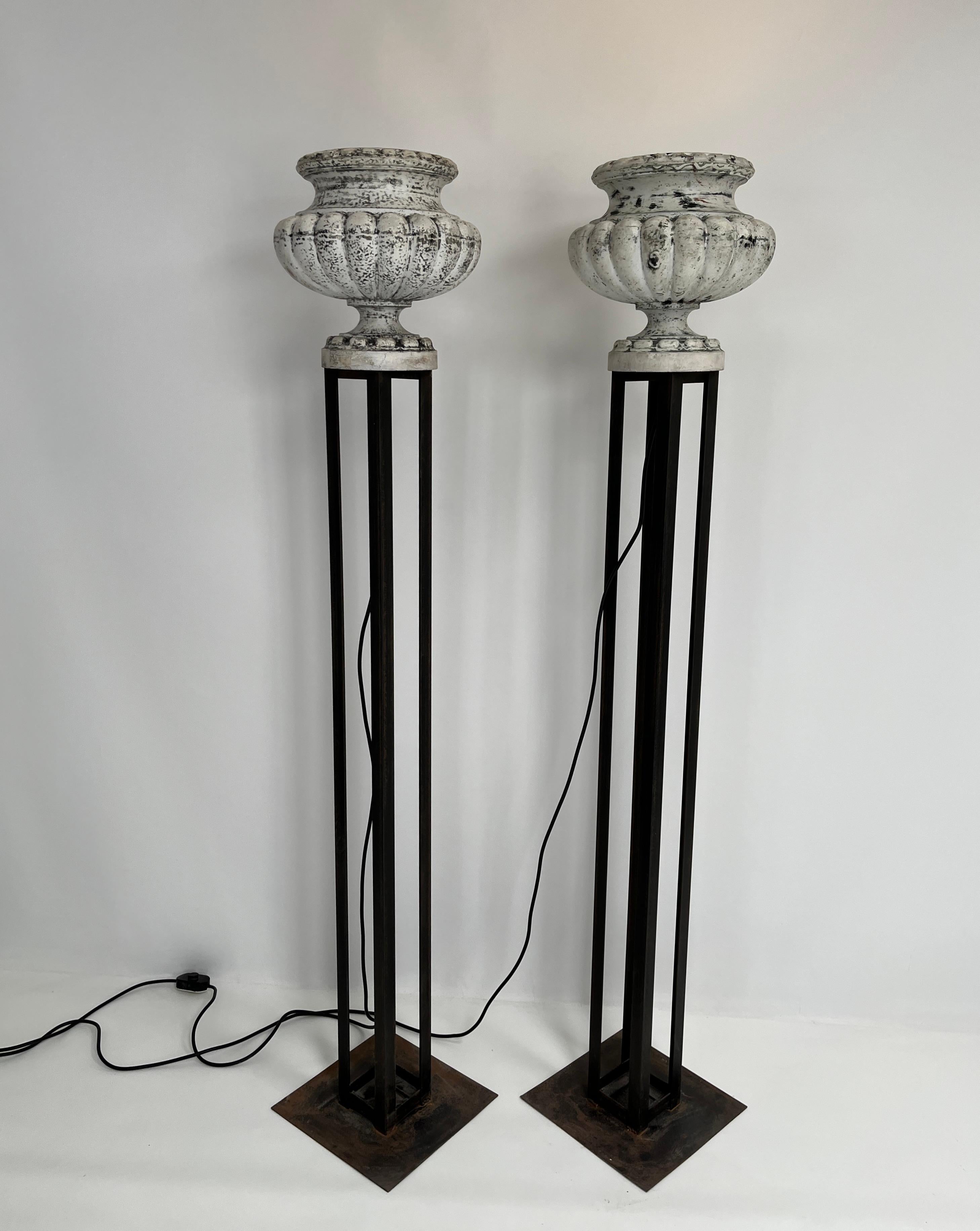 Unique pair of tall floor lamps,  Created by up cycling a pair of beautiful patinated cast iron planters and mounting them on a base using gun metal angle iron supports and a metal plate.  Each light has a medium based bulb socket, and creates a
