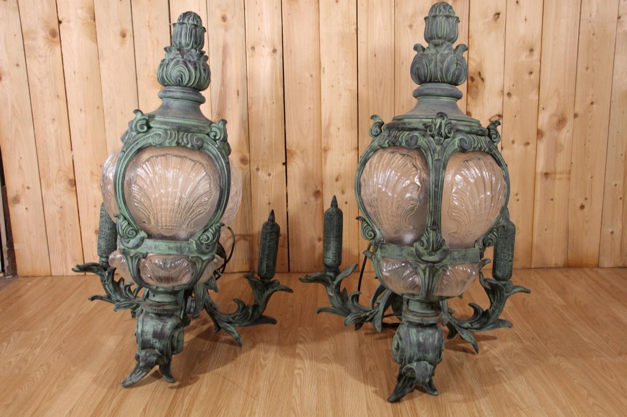 Beautiful pair of cast iron wall lights with bronze patina made after models from the Pont Alexandre III in Paris. This pair of lanterns was designed in the 20th century as part of the Schlumpf Museum decoration project. In 1957, the Schlumpf
