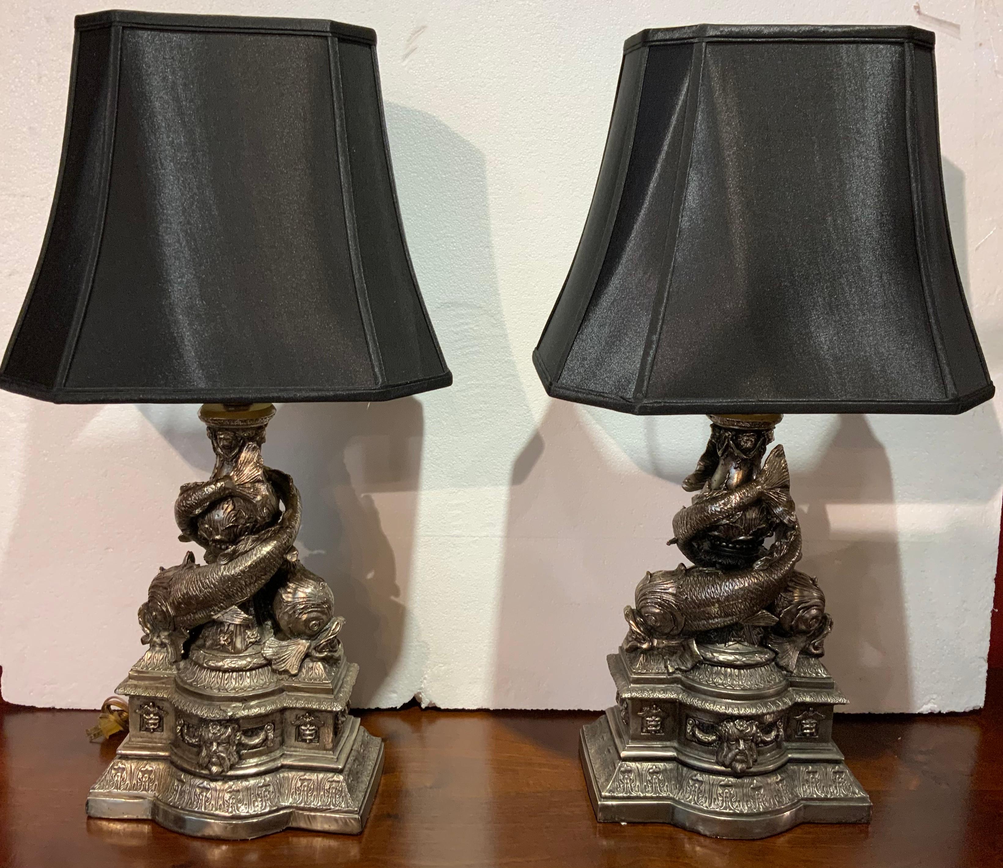 The molding on these pieces is fine quality work in the shape of intertwined 
Dolphins with bases decorated with masques and caducei, resting on
Ogden bases molded with acanthus leaves, mounted with shades. The
Color is in a muted pewter metal