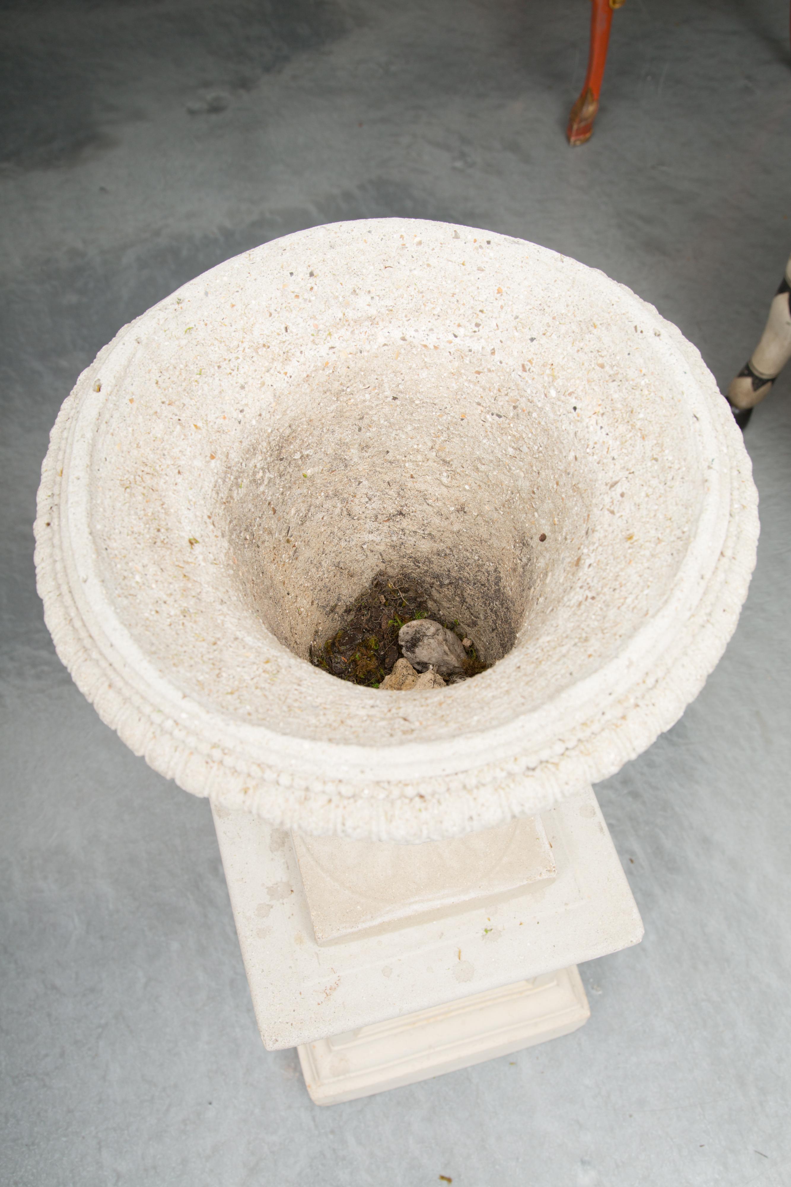 This is a pair of cast neoclassical urns on plinths with over-all relief depicting antique Grecian figures.