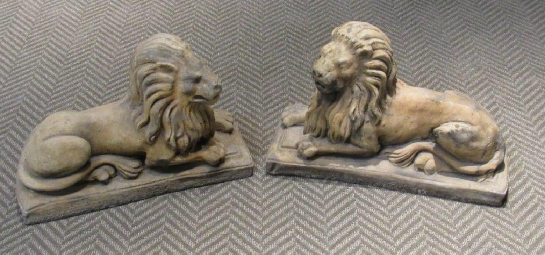 A pair of magnificent lion statues, opposing, cast stone recumbent on plinth bases. The pair of would be a wonderful addition to an entrance, garden or any living space.
       