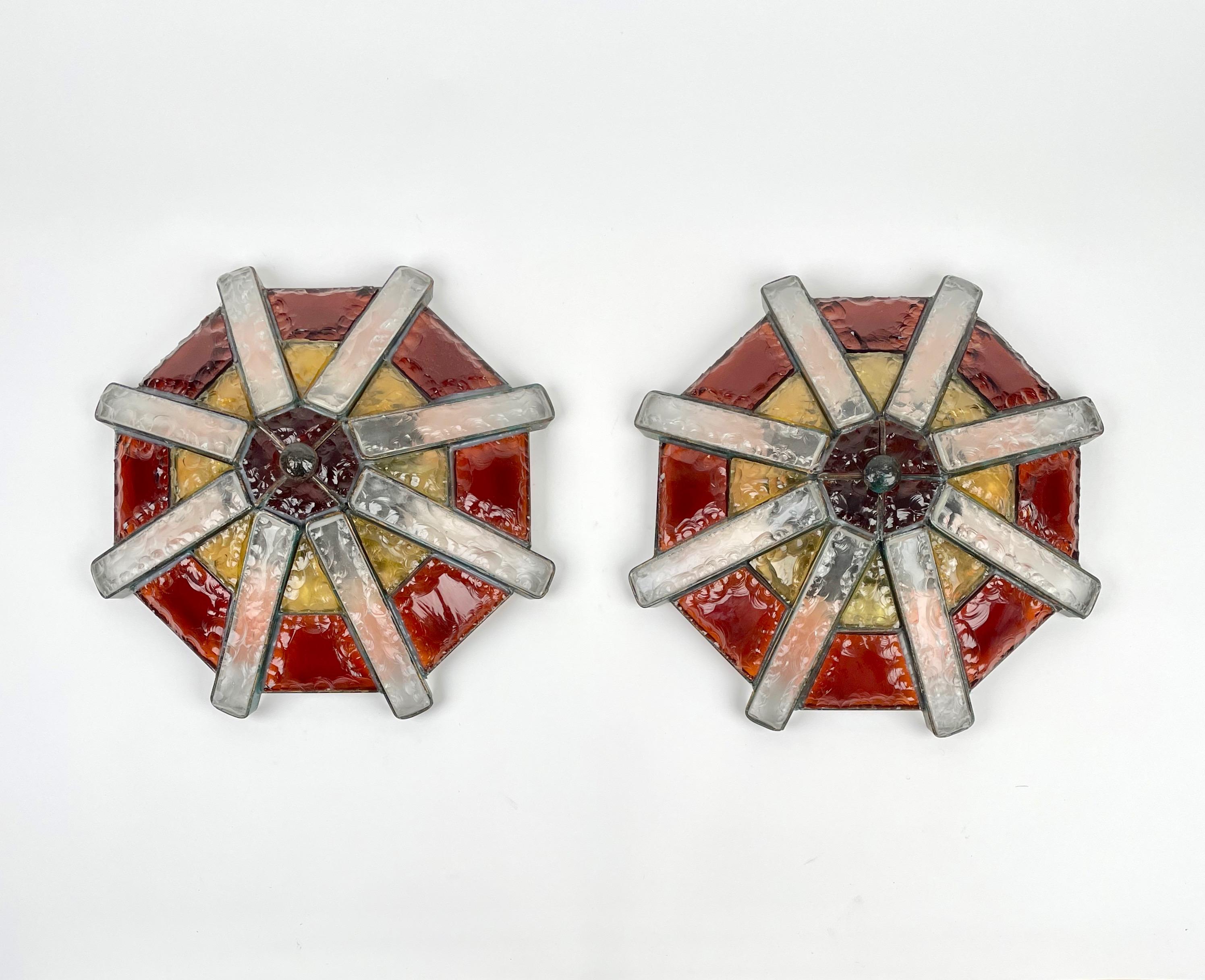 Pair of large flush mount ceiling lamps attributed to Poliarte in Verona, Italy, 1970s. The lamp radiates in geometric segments of alternating translucent and colored hand chipped glass creating a circular relief to break the light, in red, white