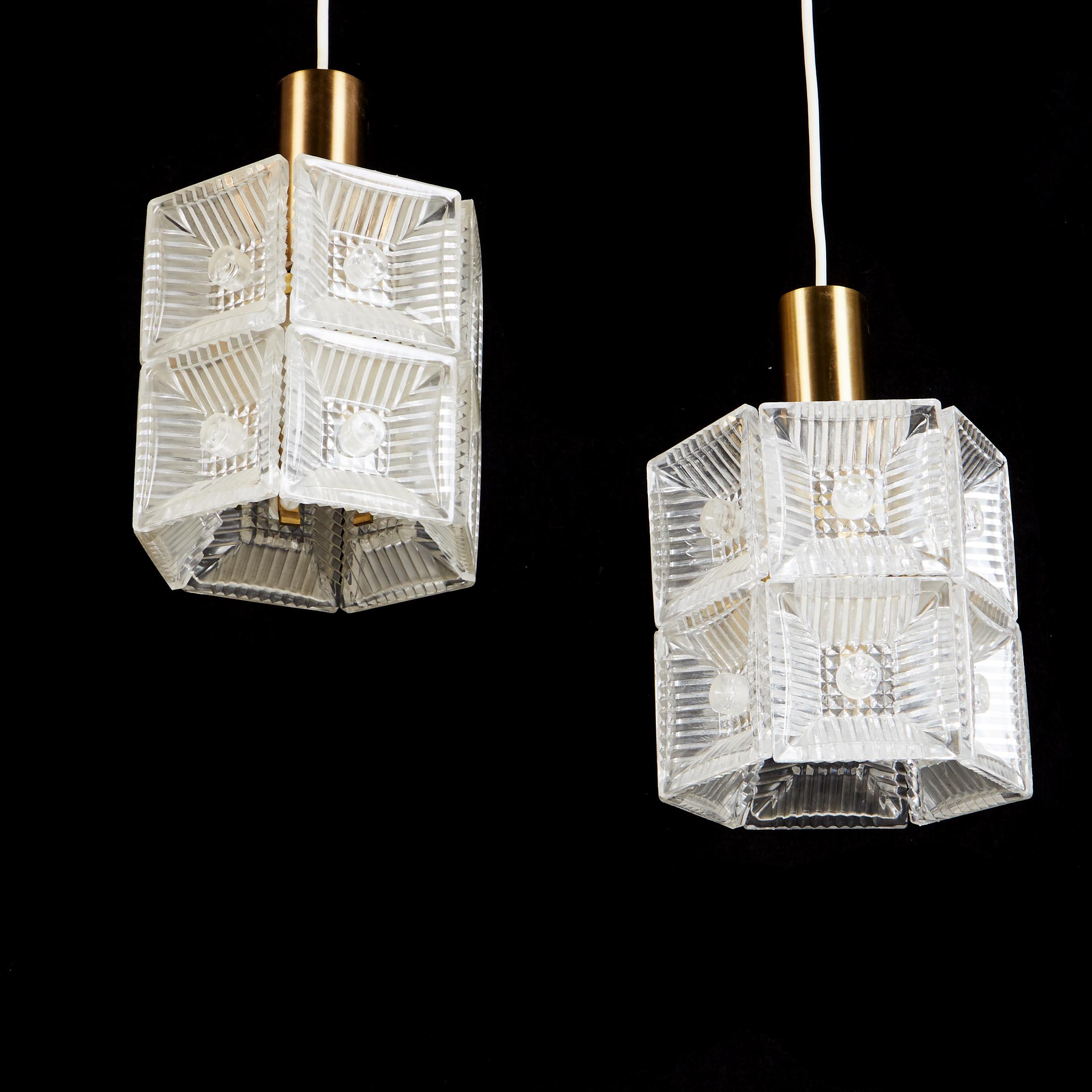 Brass construction with pressed glass, fitted with one E27 sockets, designed in the 1960s in Sweden by Carl Fagerlund for Orrefors Glassworks. Glass part height about 16 cm, total height about 24 cm each, diameter about 15 cm.
 