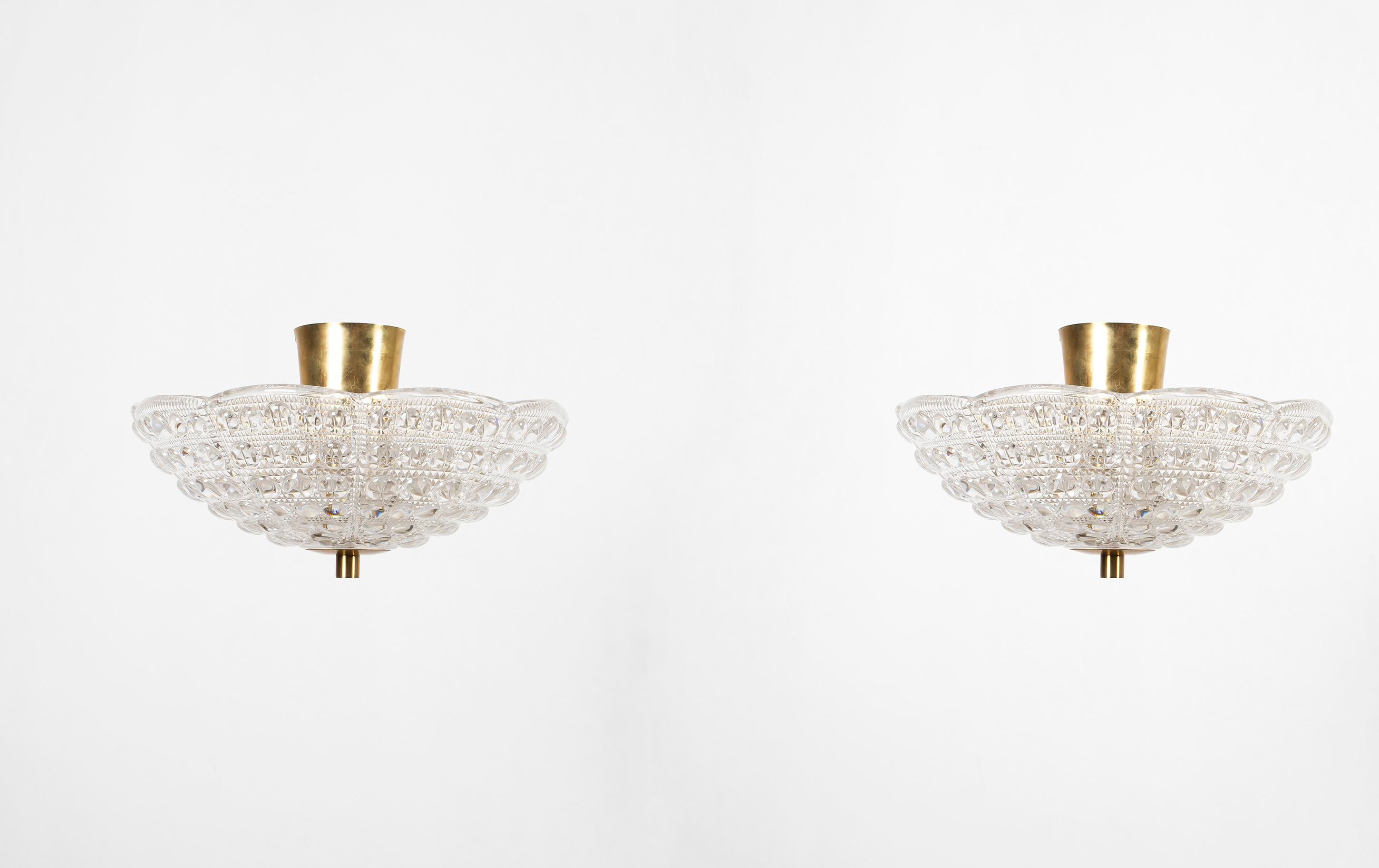 Pair of decorative flush mount lights with heavy crystal glass shade and brass base. Designed by Carl Fagerlund and made in Sweden by Orrefors. Both lamps are fully working and in good vintage condition. They are each fitted with three E27 bulb