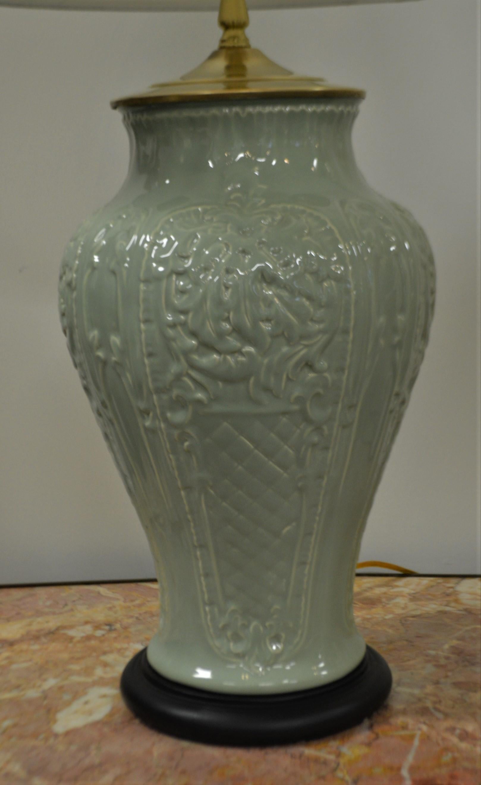 Attractive, decorative embossed design, large and heavy celadon ceramic lamps having a hint of chinoiserie style. Excellent quality with solid brass topping the ceramic and interesting brass finials. 
The shades have been recently made in an off