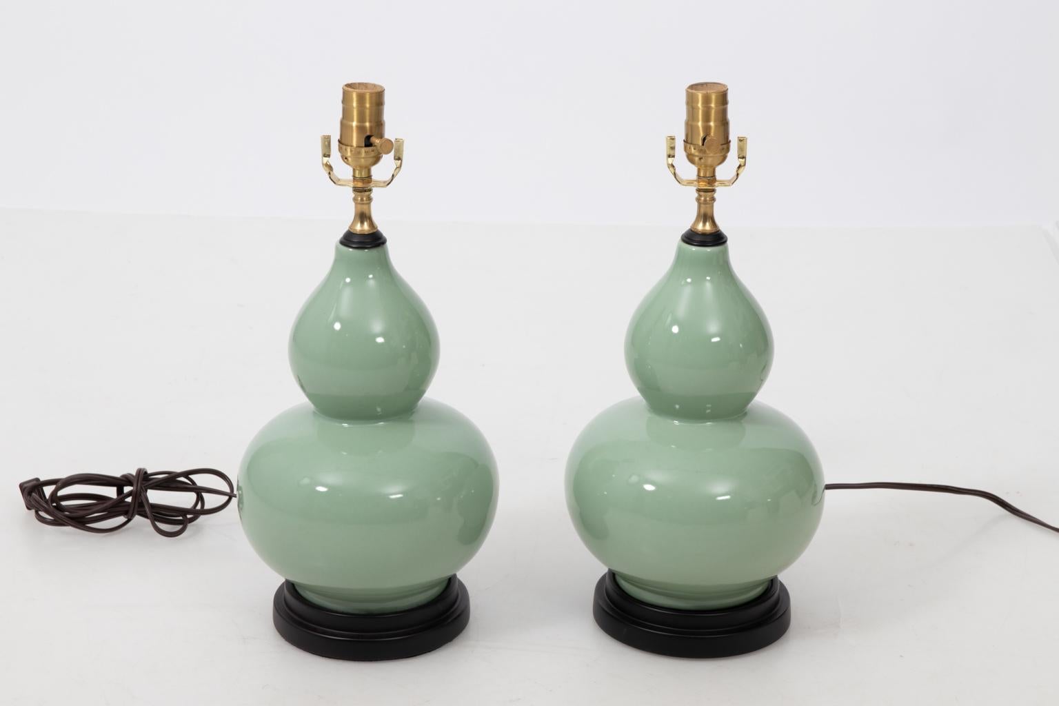 Pair of ceramic celadon gourd shaped table lamps on black turned bases with celadon finials, circa 1980s. Please note of wear consistent with age including finish loss on the body and rim. Made in China. Shades not included.