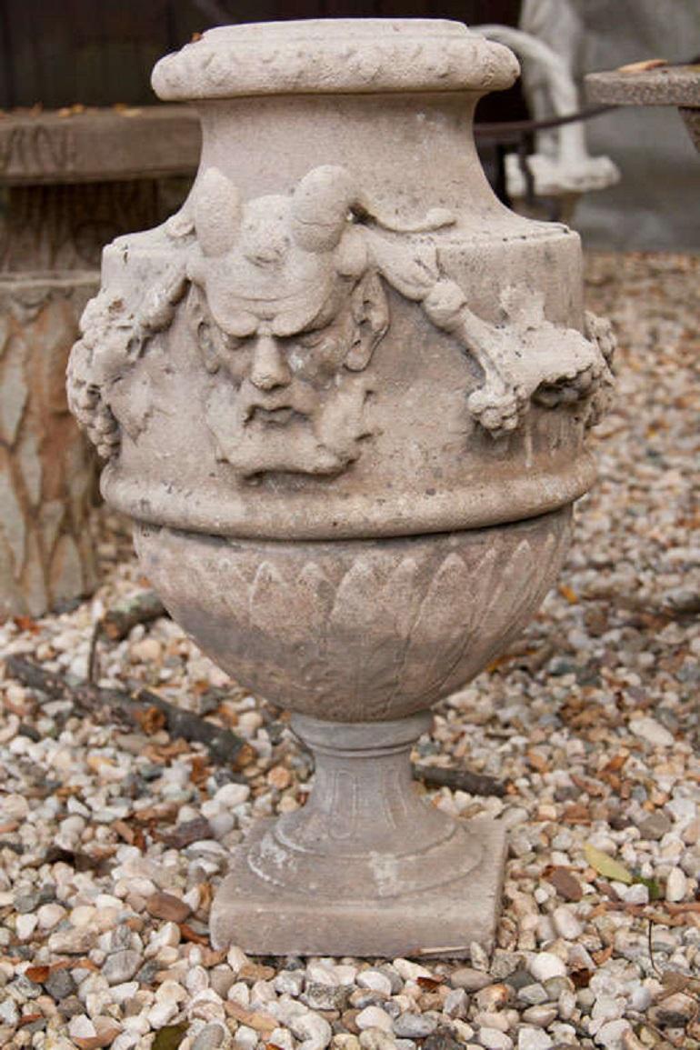 Pair of cement urns depicting the Greek god pan.