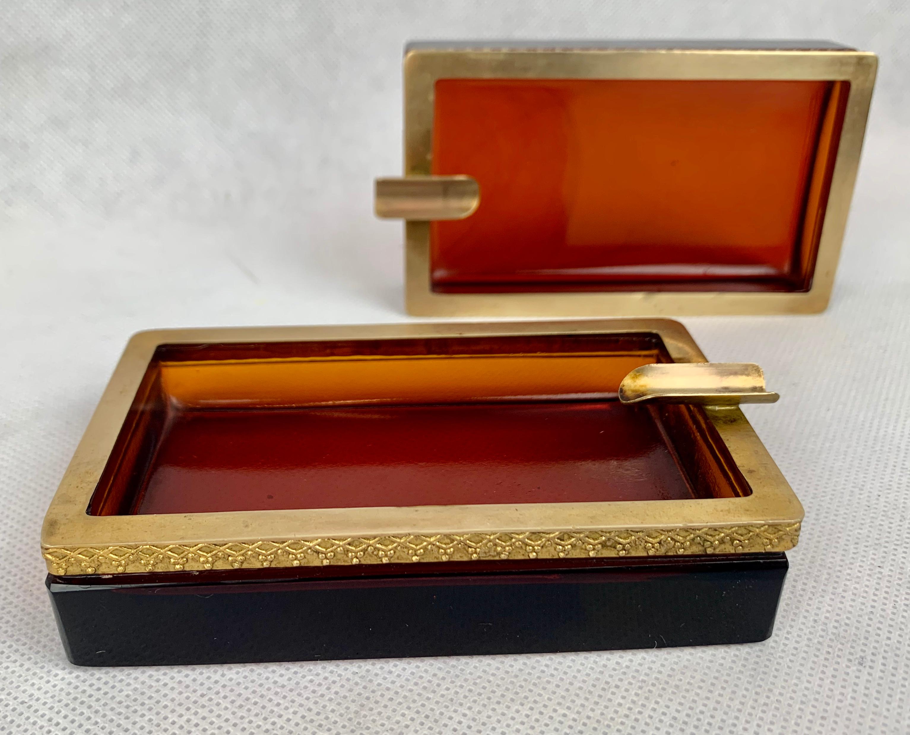 Pair of Cenedese Murano glass gorgeous amber and gold ashtrays. The warm amber color is enhanced by the gilt border in relief. There is some darkening of the border due to cigarette usage. Don't smoke, use them for munchies on a coffee table or as a