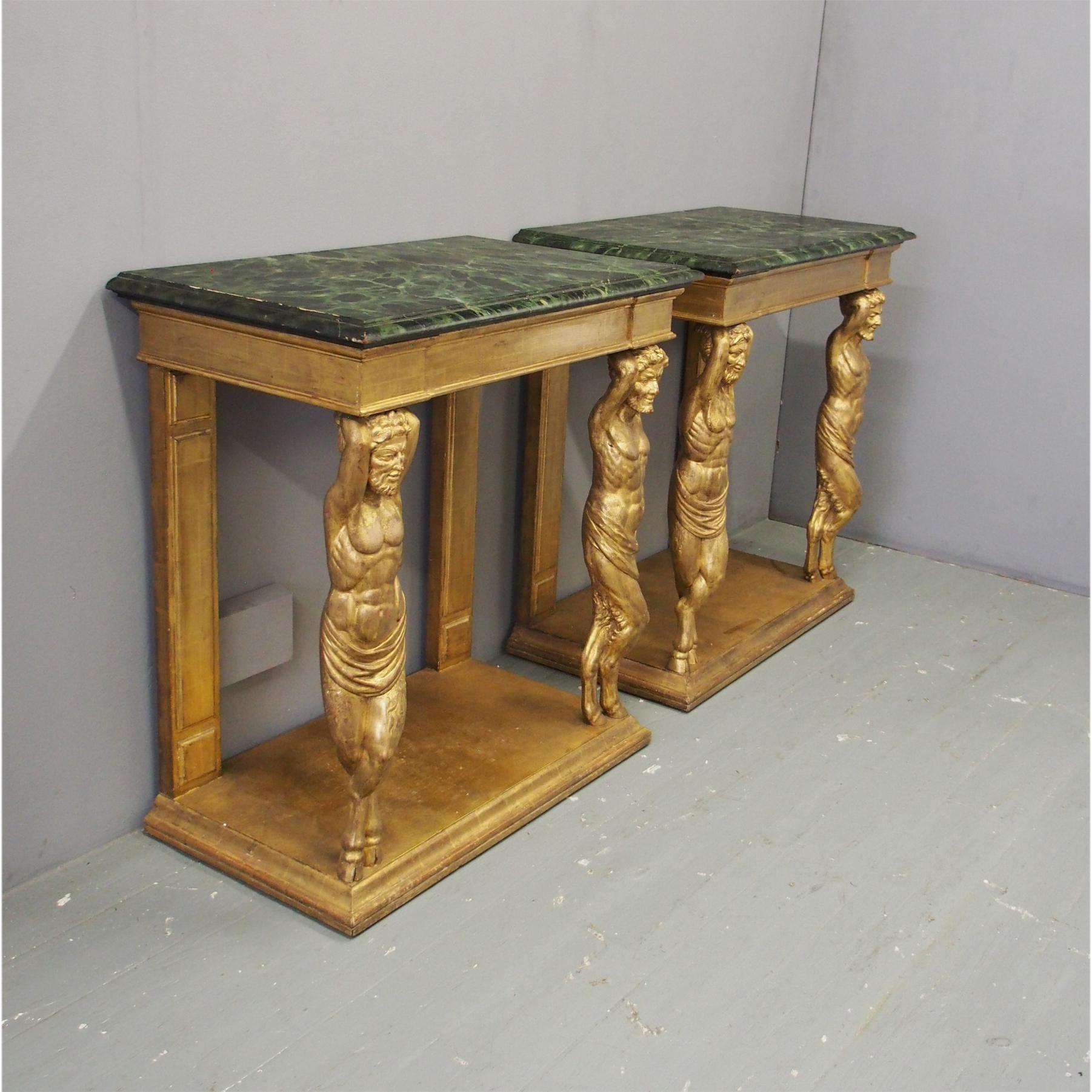 Pair of console tables, circa 1900. With rectangular green variegated faux marble tops and a gilded, shaped frieze (with marks from the sheets of gold leaf) and held in place by 2 centaurs to the front and rectangular legs with fielded panels. The