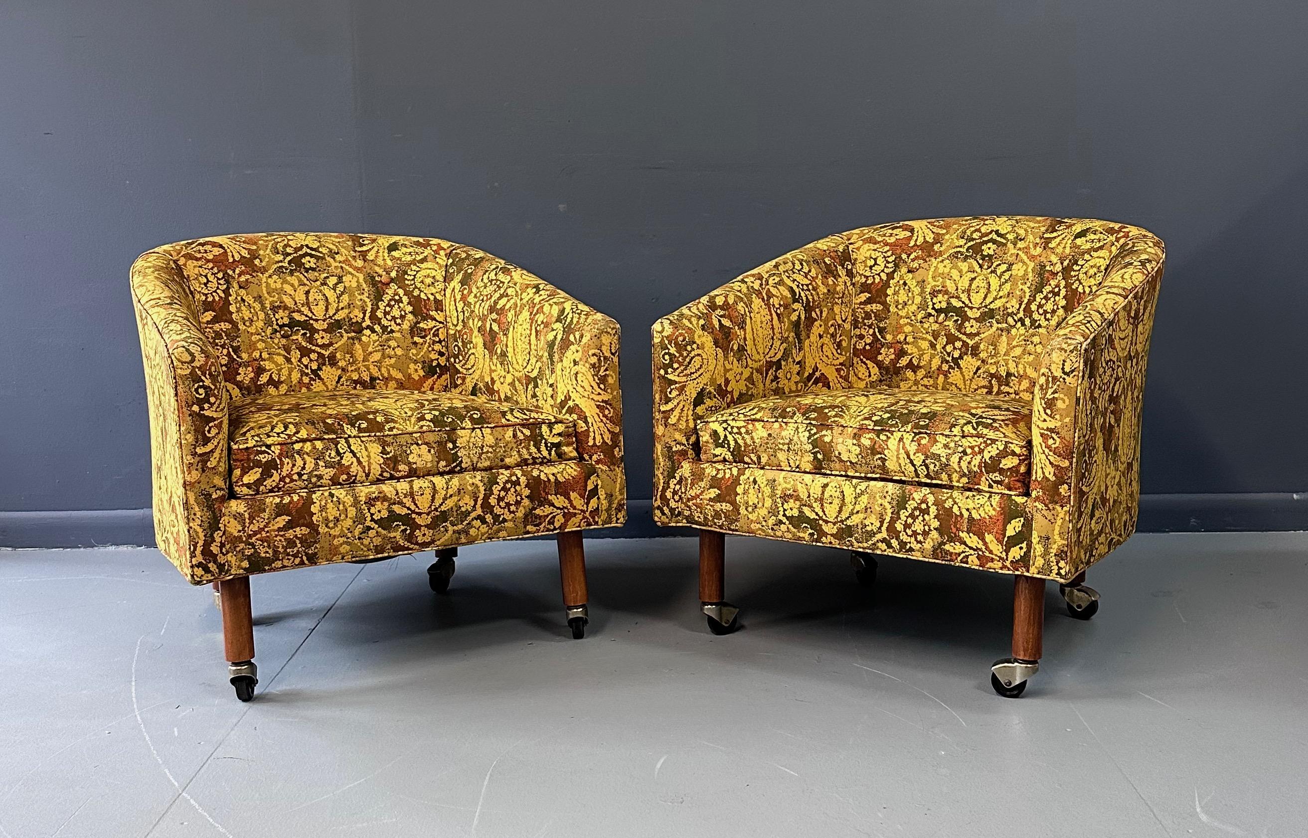 Great pair of barrel chairs in a very cool batik fabric. These chairs are classic lounge chairs with generous proportions and walnut legs with casters.