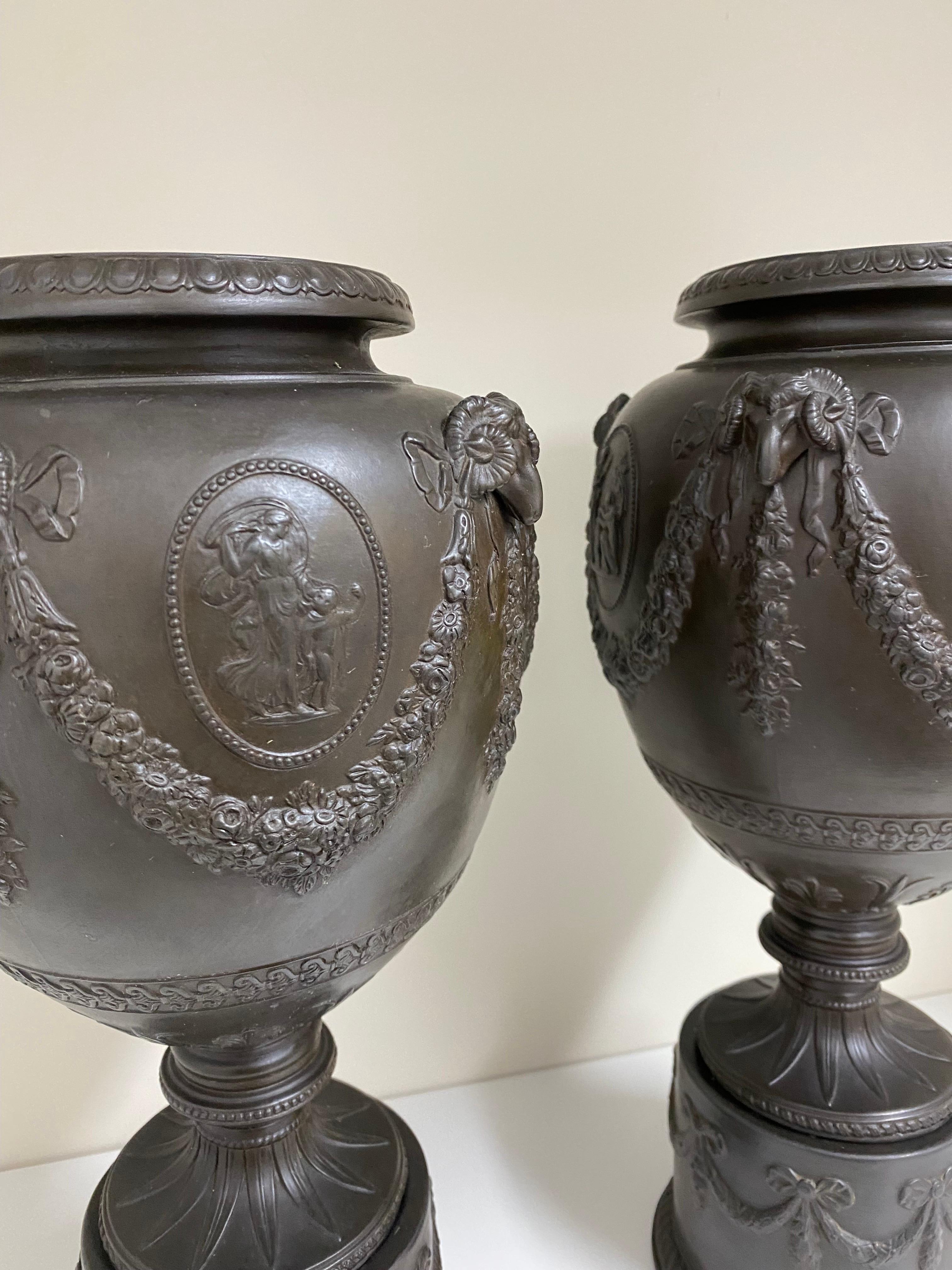 A pair of black basalt relief urns on on bases.