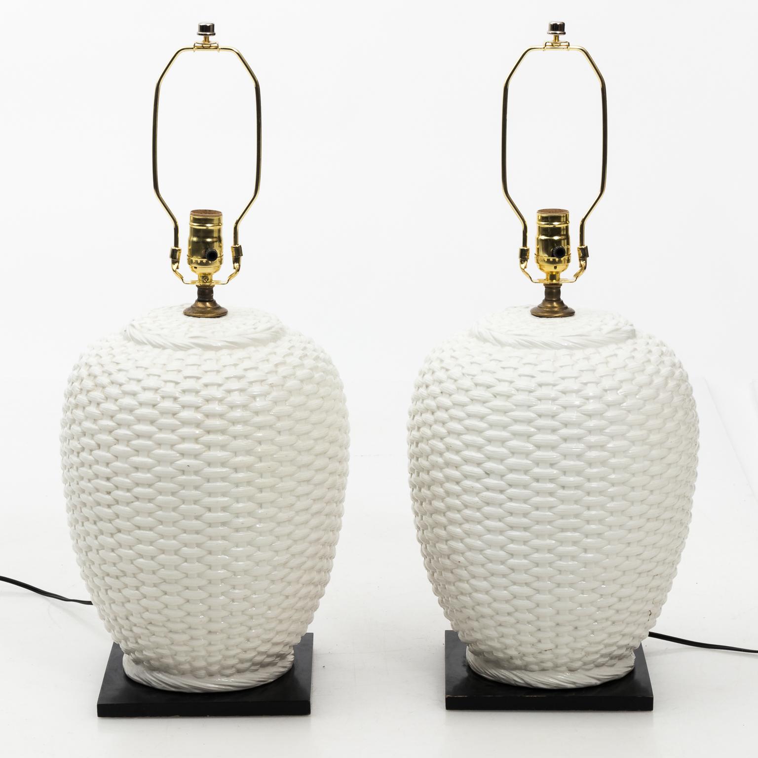 Pair of mid-20th century white ceramic basket weave lamps with drum shaped linen shades. Please note of a minor chip on the corner of the wood base.