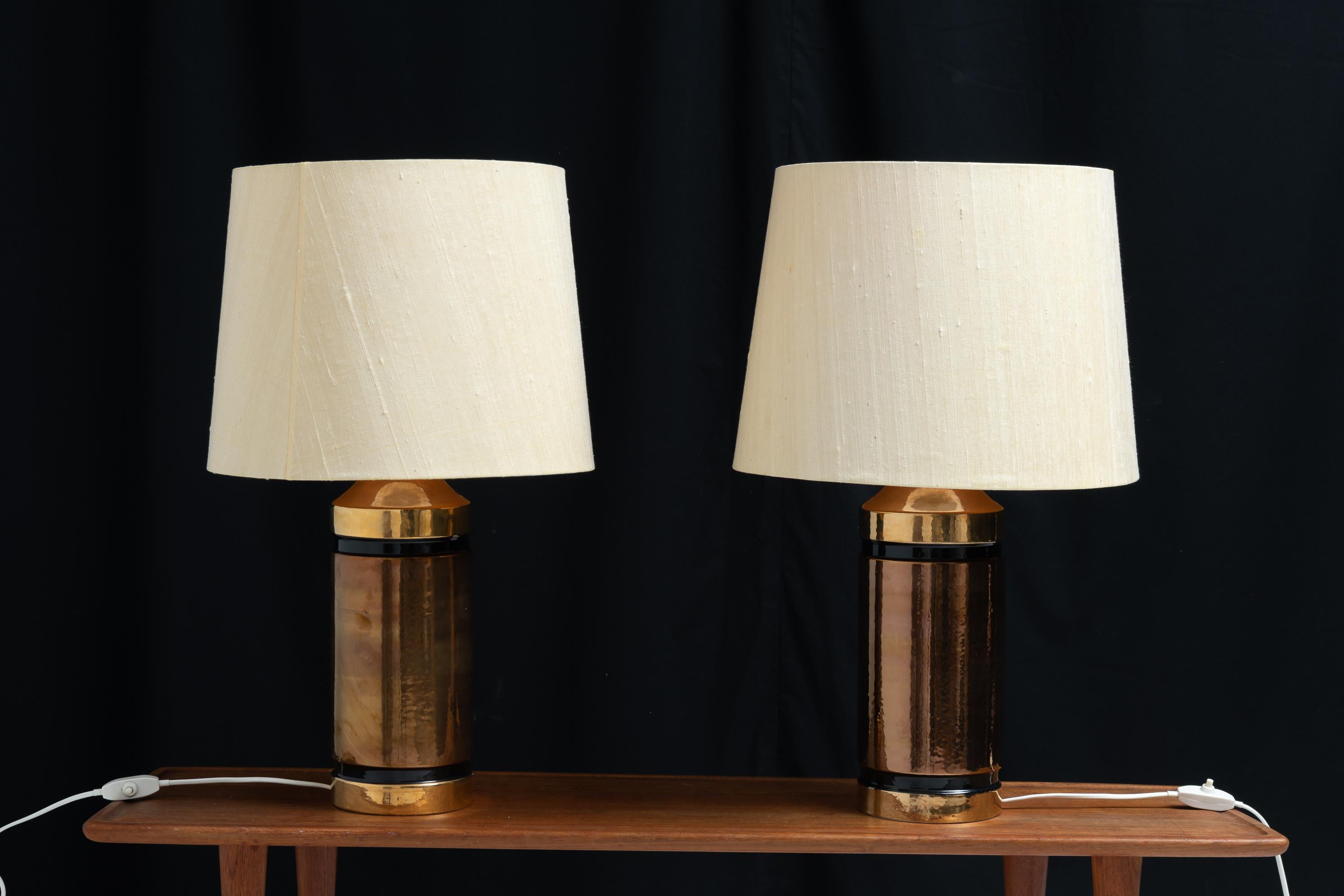 Pair of ceramic table lamps by Bitossi for Bergboms in Sweden. The pair are likely from the 1970s and have a cylindrical base and warm colours. The shades are the original shades to the lamps but they are slightly faded from time. The lamps were