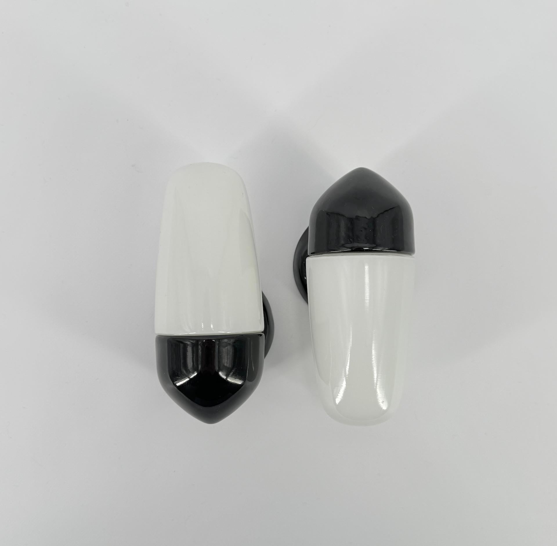 Wall light in black porcelain and opaline glass shades were designed by the German designer Wilhelm Wagenfeld, who studied at the Bauhaus school. 

This model dates from 1958 with sleek, round and elegant lines, a timeless design that will look