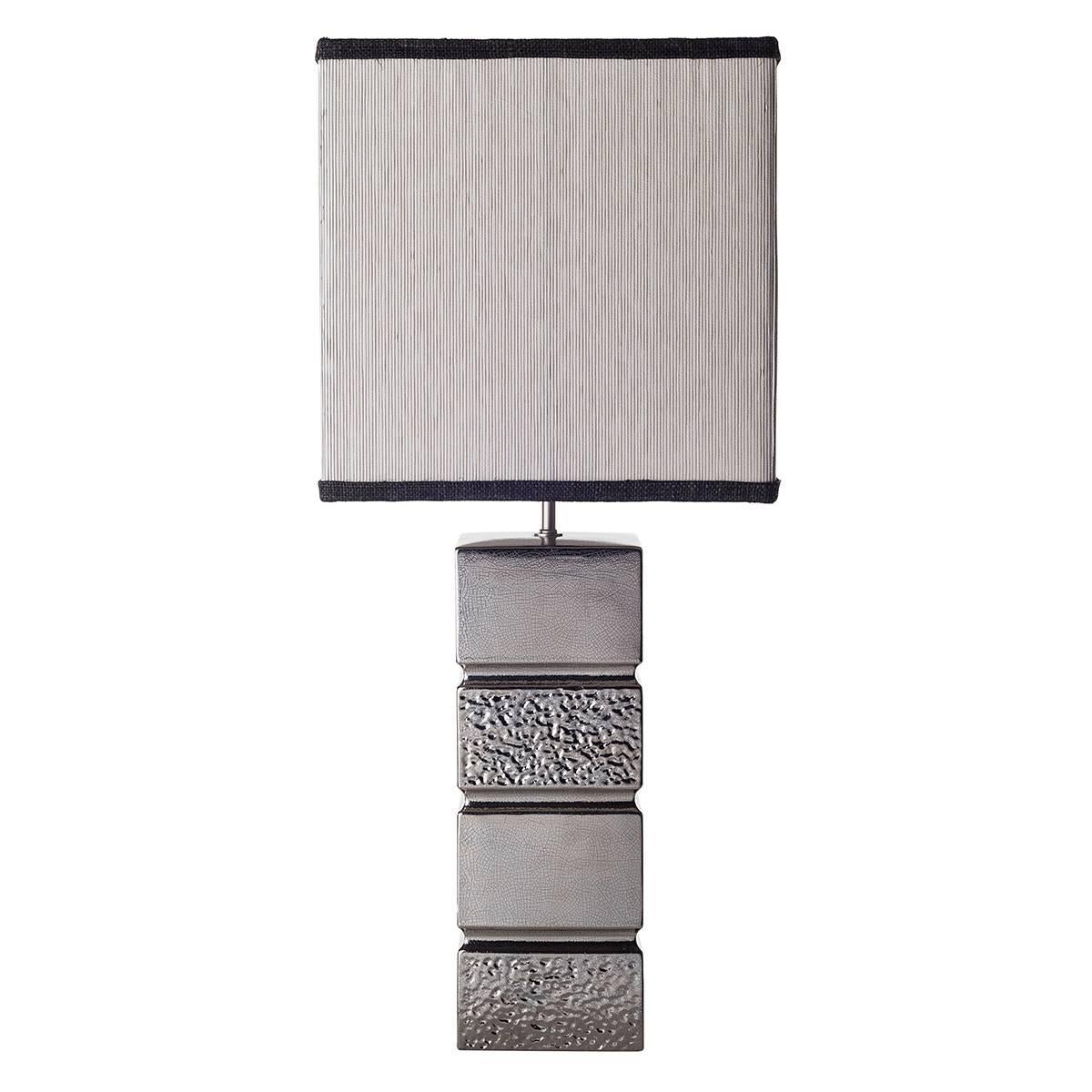 Pair of ceramic block-shaped table lamps and shades.

The two lamps are featured by a four blocks-structure decorated smooth and pierced. The ceramic is finished in platinum using a thin layer of the precious material hand brushed on the glazed