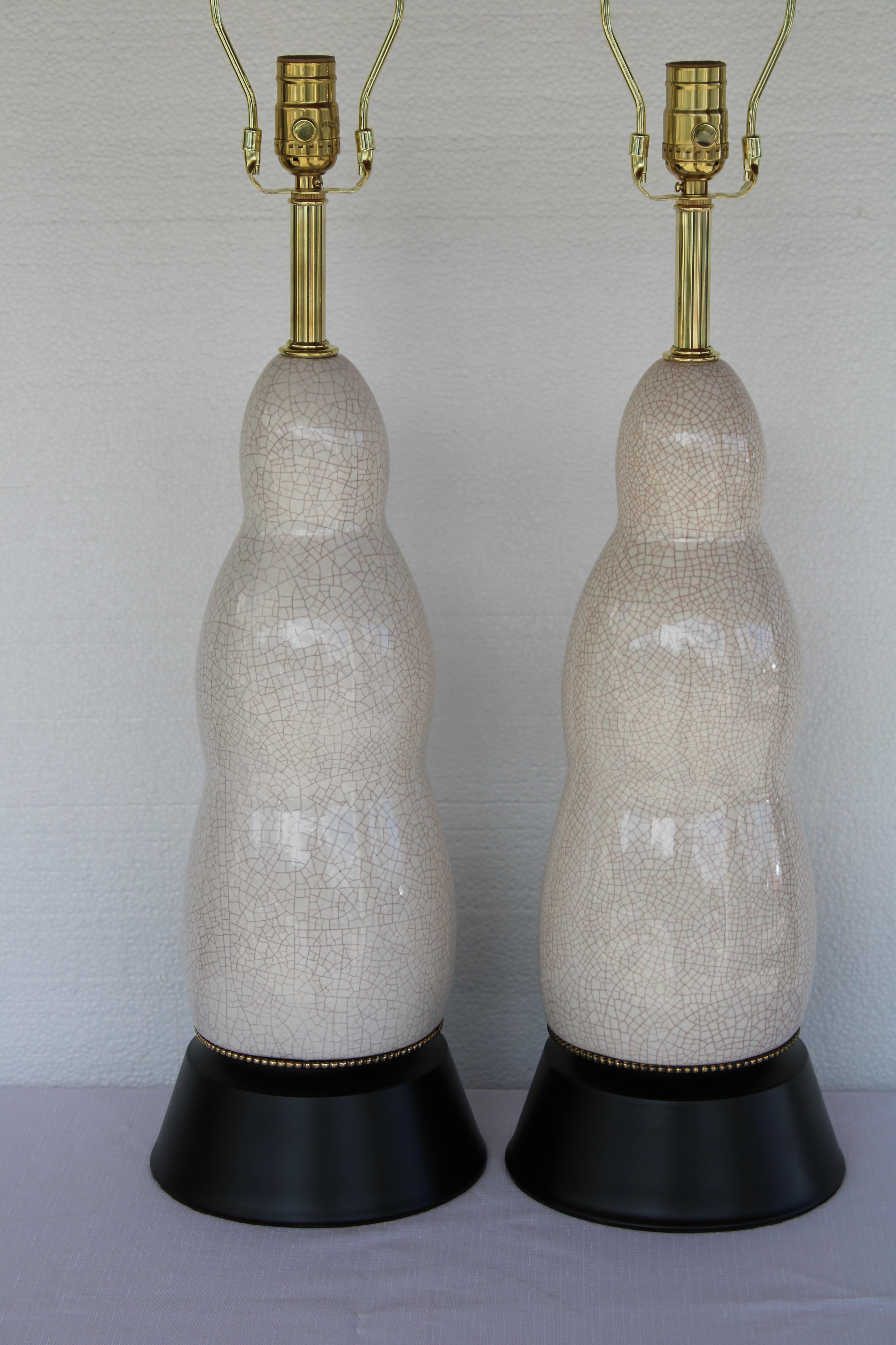 Pair of ceramic crackle glazee lamps.  Lamps have been professionally rewired for 3 way light bulbs. We painted the bases black and added new brass necks and high quality brass hardware.  Lamps measure 24