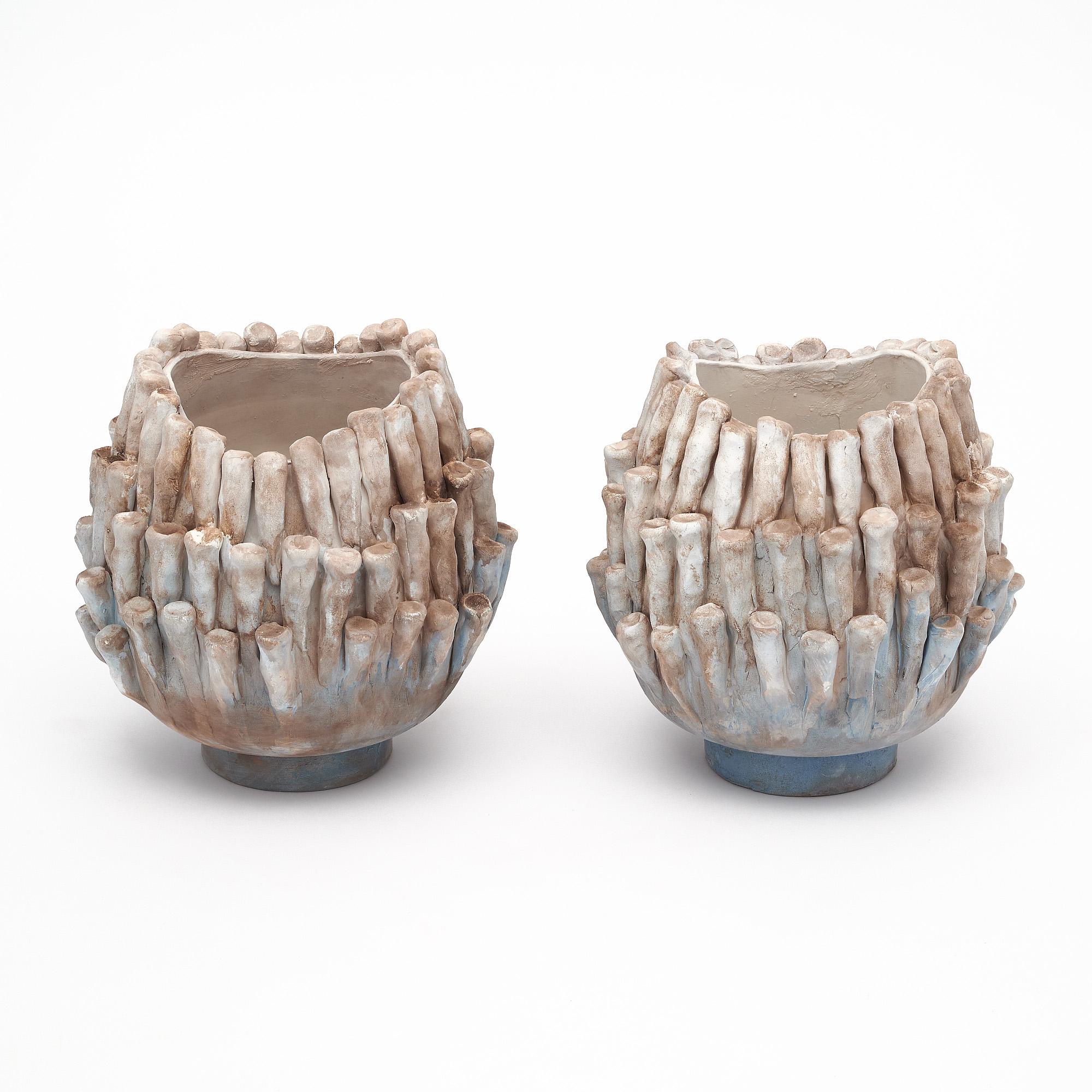 Pair of ceramic vases from Vallauris, France. The vases feature elements reminiscent of coral and have a striking organic appearance. The finish features tones of terracotta, blue, and cream.