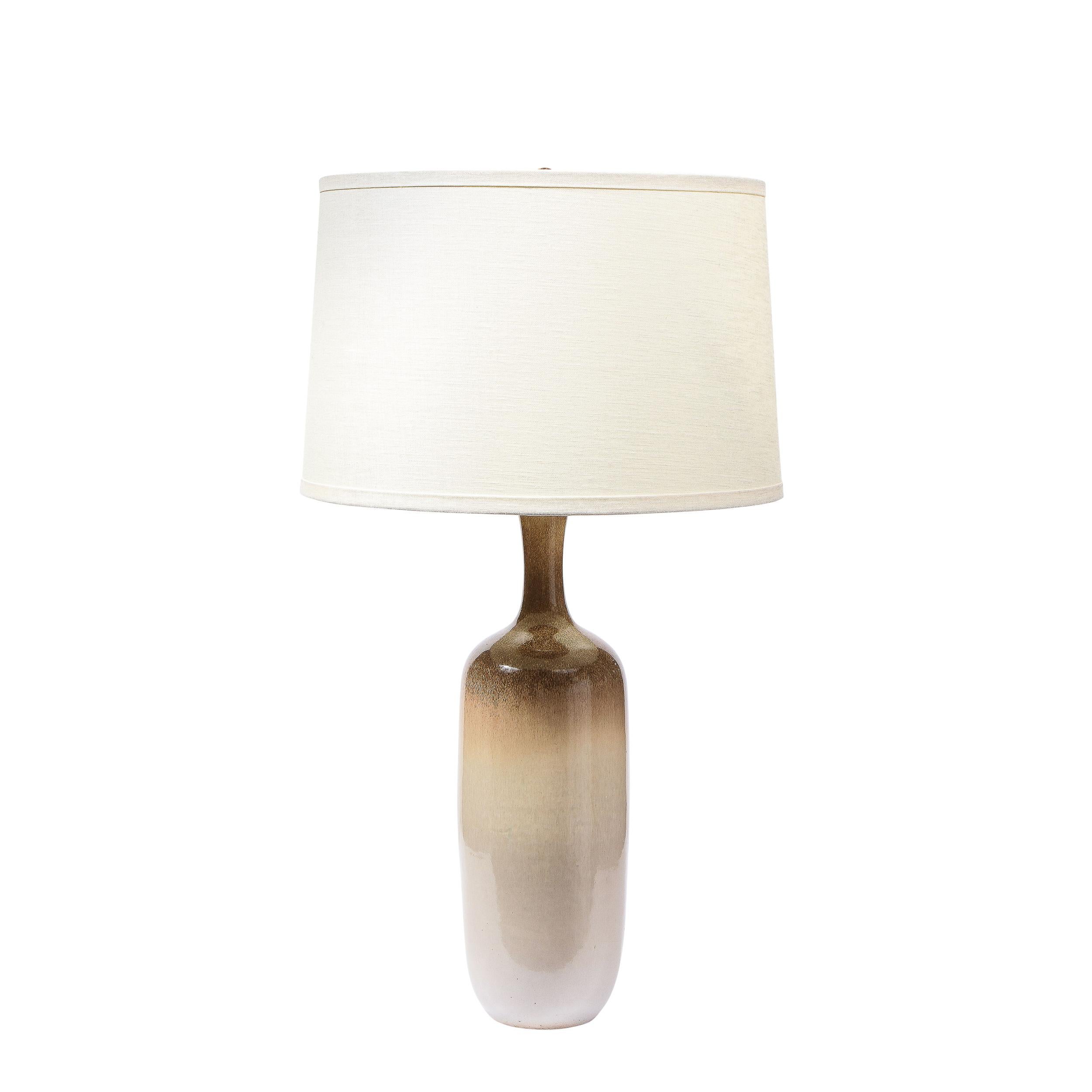 This refined and sophisticated pair of Mid Century Modern table lamps were realized by the esteemed maker Design Techniques in the United States circa 1970. The feature cylindrical bodies that taper slightly at their base and shoulders hand painted