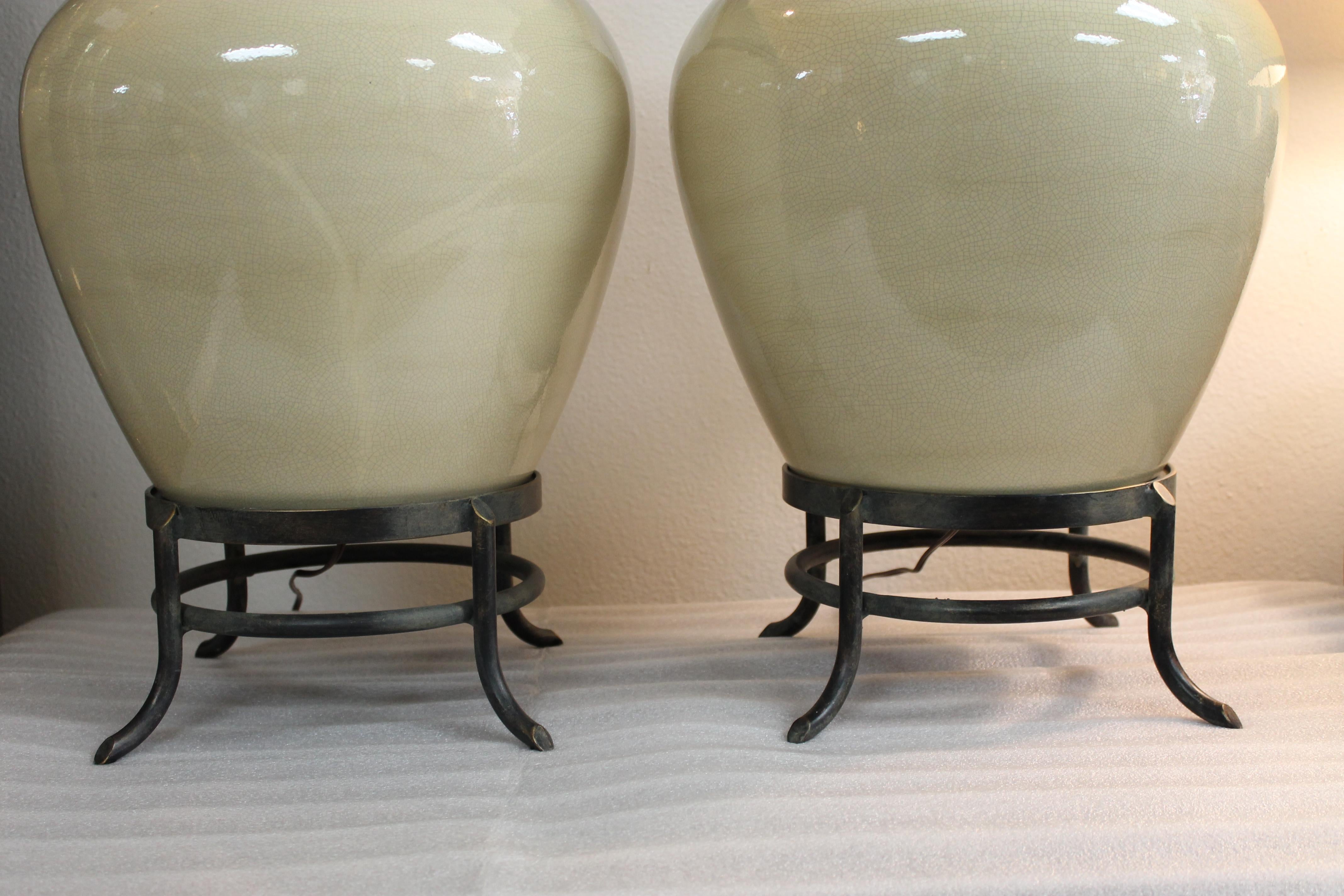 Pair of ivory jar lamps. These lamps have a crackle glaze throughout. Steel base and neck brace. They measure 23.5