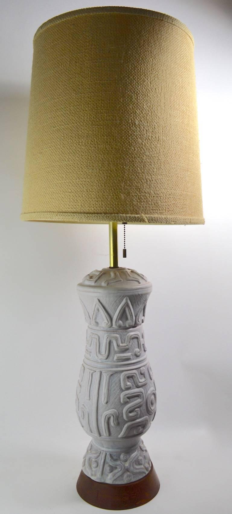 Very stylish and sophisticated pair of ceramic lamps, designed by Gerald Thurston, for Lightolier. The ceramic body has an Aztec influence motif, each mounted on a solid wood plinth base (finish on base shows wear). Both have three sockets, which