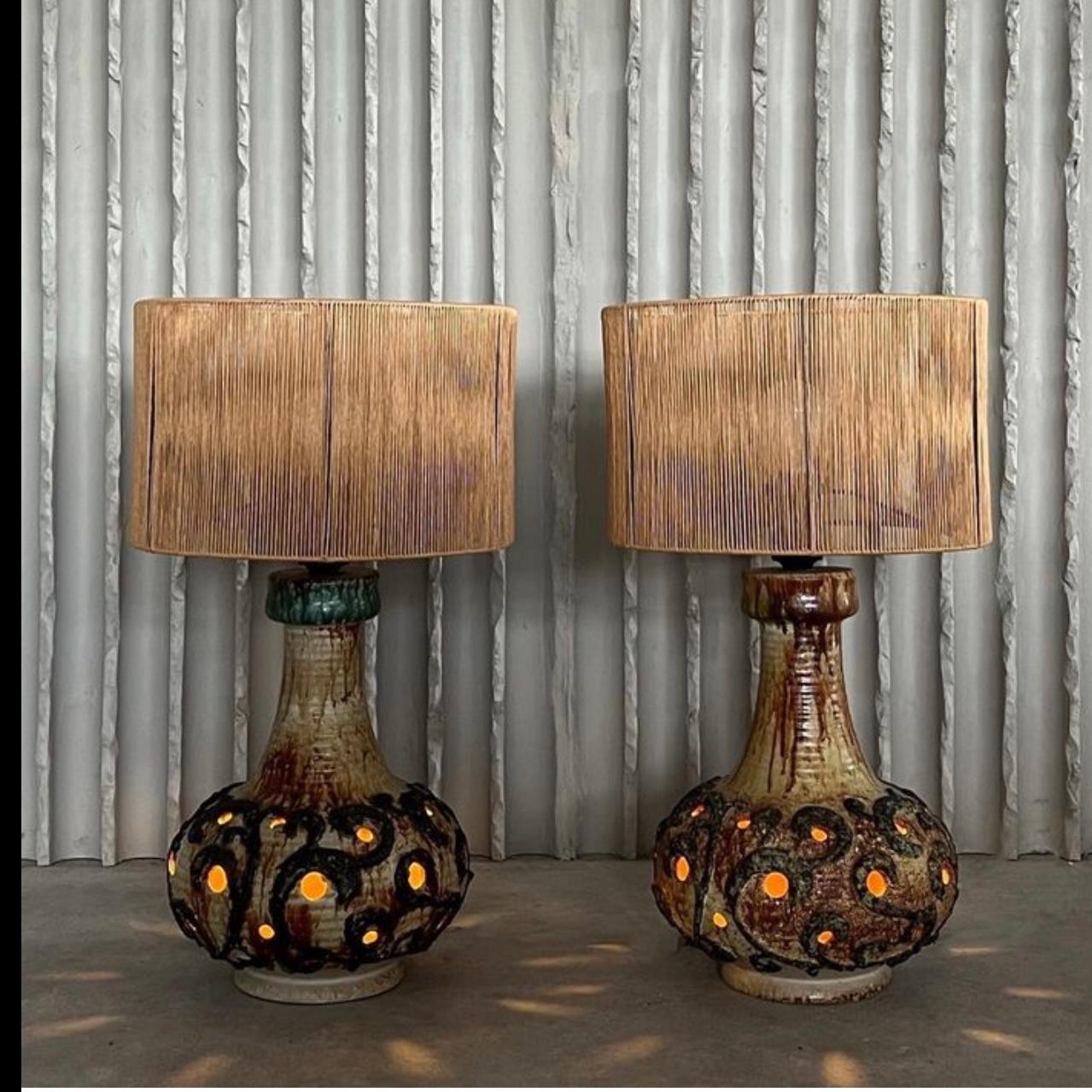 Pair of unusual earthy colored studio pottery lamps with exceptional texture and glazing and vertical rope shades.  The interior of the base lights up to cast warm glow.

Holland, circa 1970

Dimensions: 13W x 13 D x 23H (with shade)