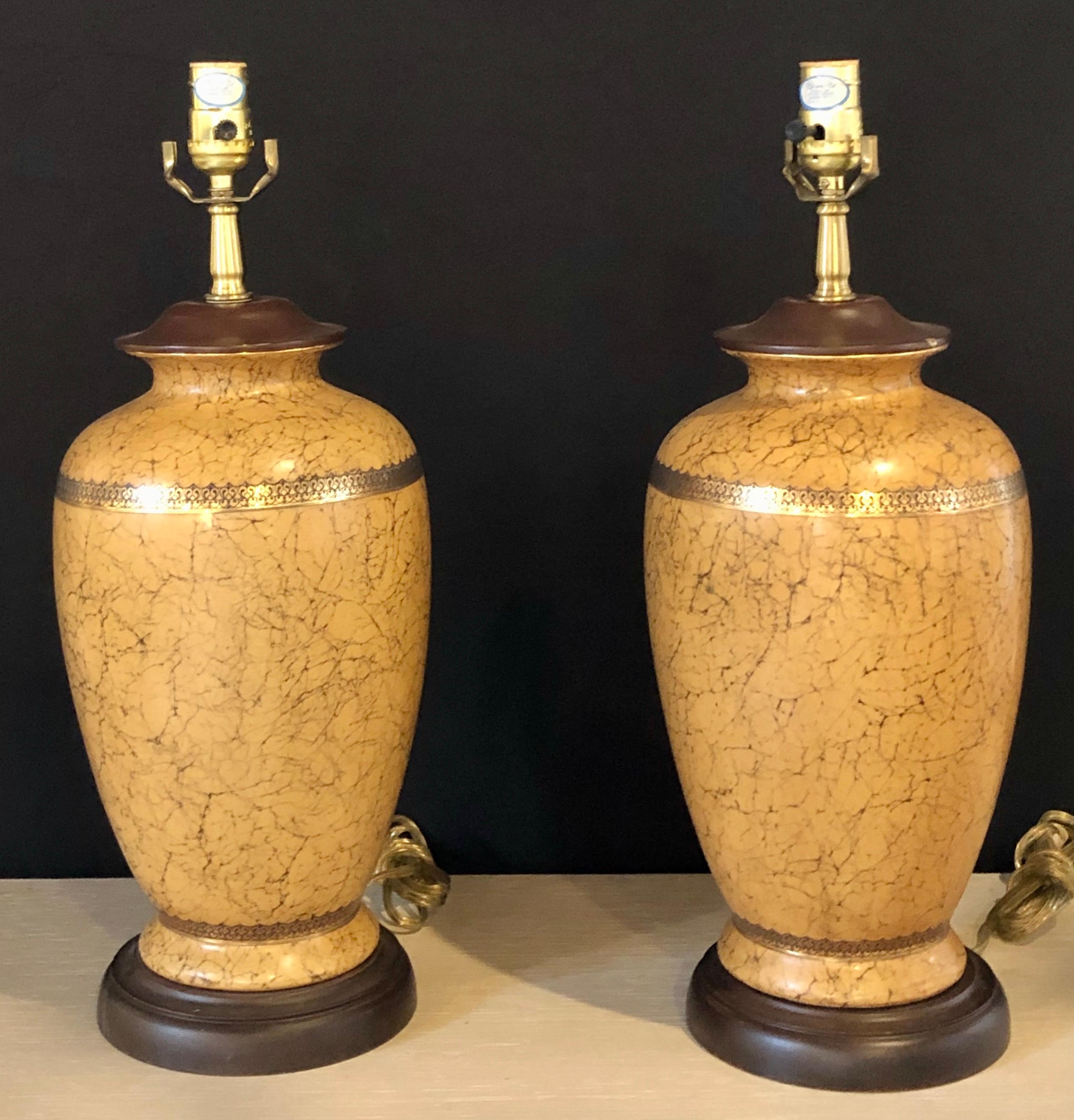 Pair of ceramic lamps with gold trim and crackle finish wooden base bottom.