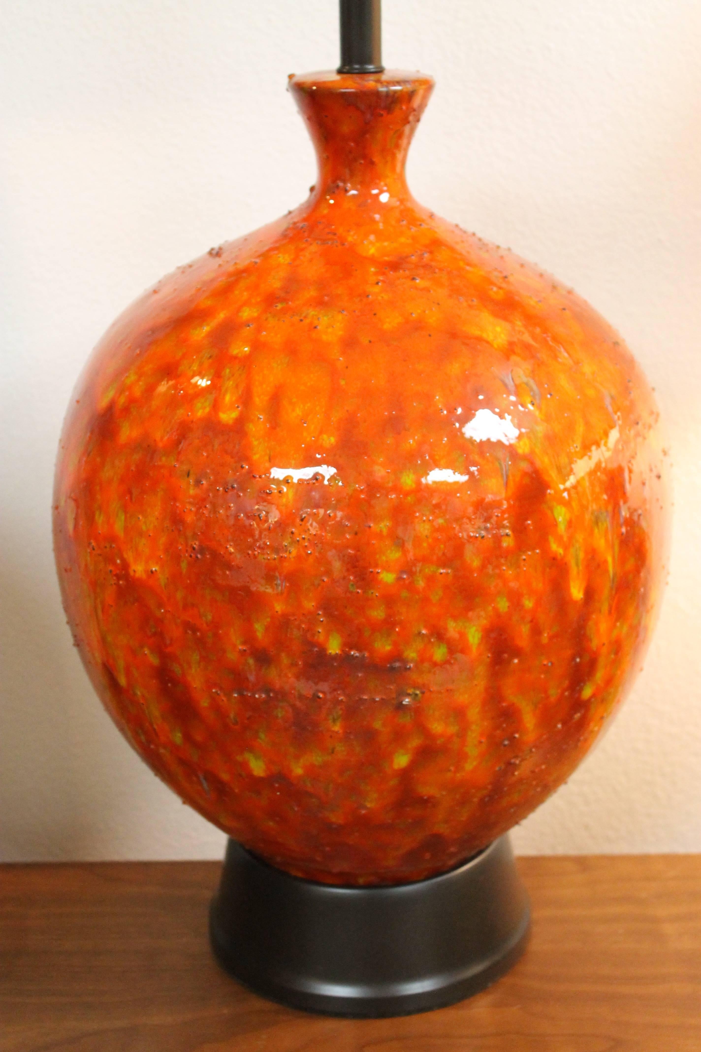 Bulbous pair of ceramic lamps with a mixture of orange, yellow and orange glazes and bubble bursts. These lamps have been professionally rewired. Total height is 23