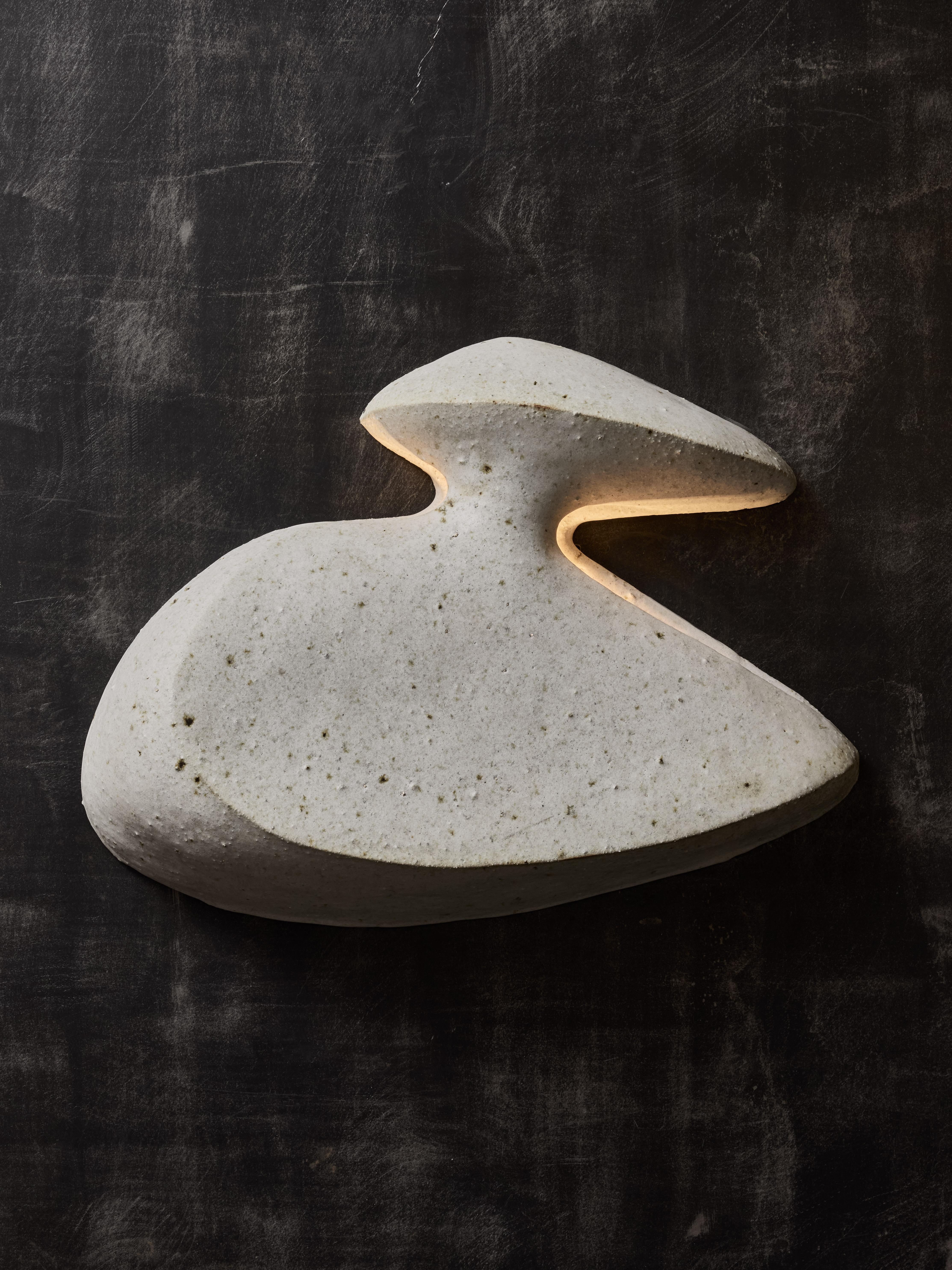 Pair of free shaped ceramic wall sconces by the contemporary artist Natasha Dakhli.

These wall sconces let the light go through thanks to two side slits and can be positioned on the wall in any direction thanks to several attach points.

Signed at