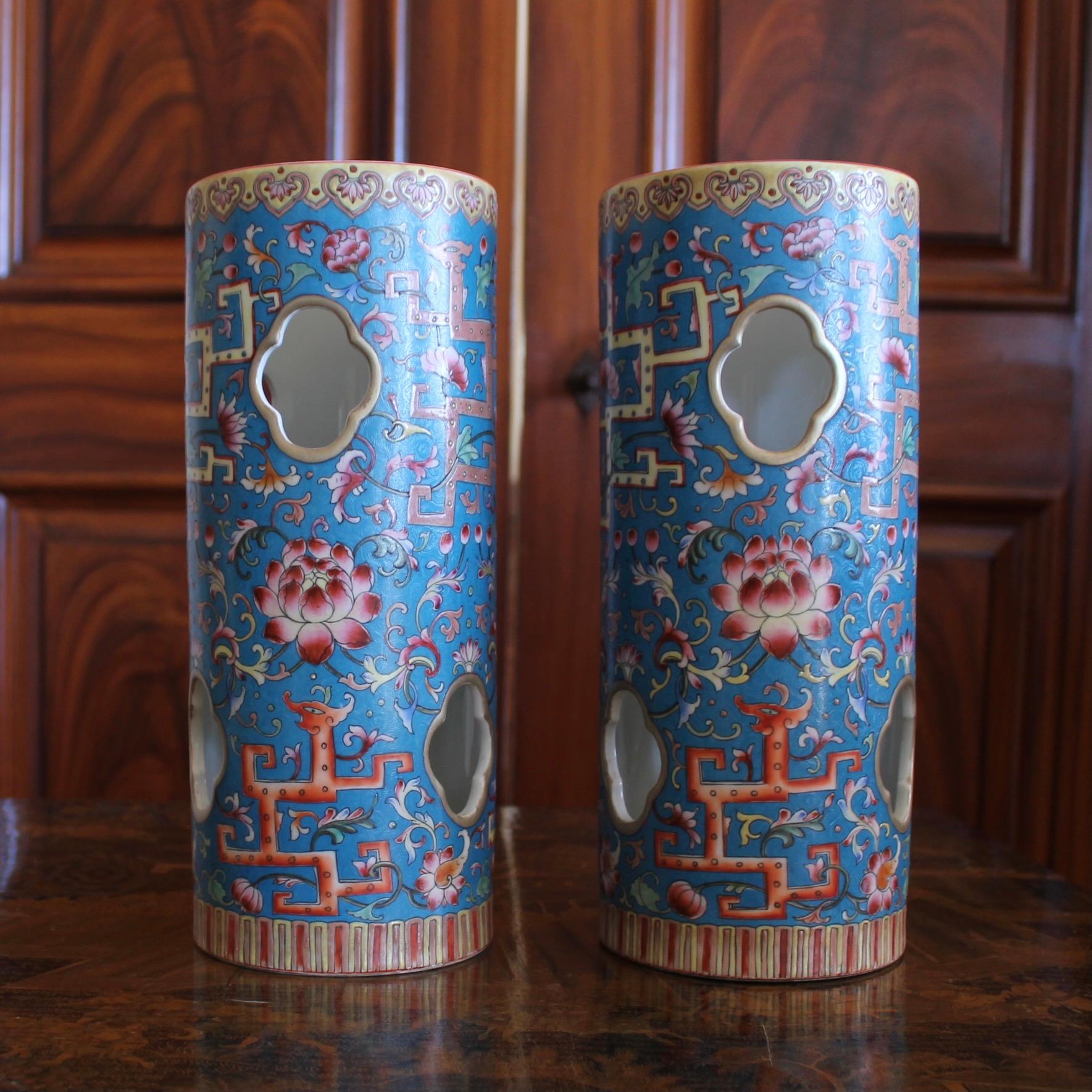 A beautiful pair of polychrome porcelain cylinders, with bright enameled zoomorphic and foliate decoration in orange, rose, green and yellow on a striking and rare patterned ground color: cerulean blue. Quatrefoil piercings are spaced around the