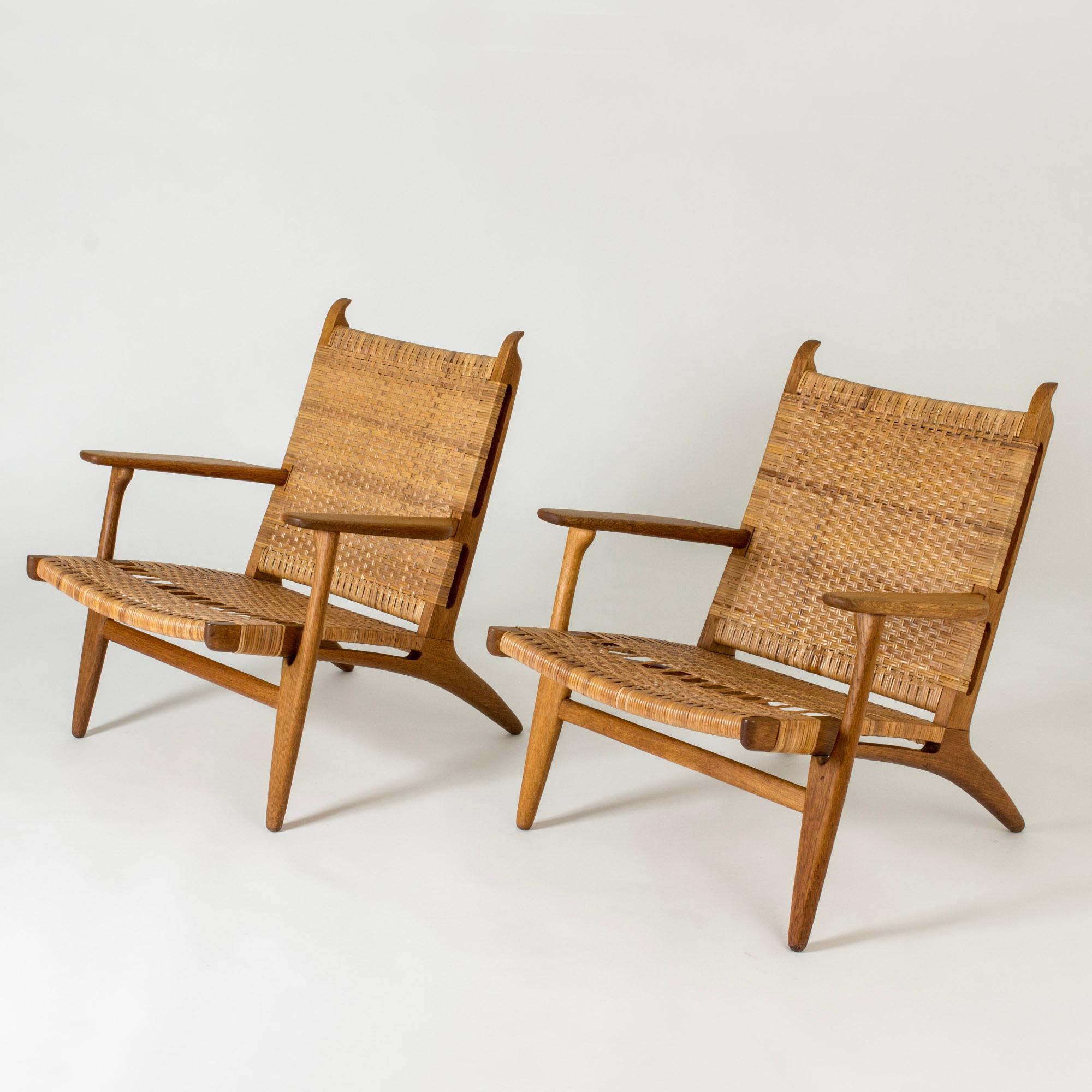 Pair of beautiful “CH 27” lounge chairs by Hans J. Wegner, made from oak and rattan. Beautiful pattern in the rattan and whimsical carved “horns” at the tops of the backs.