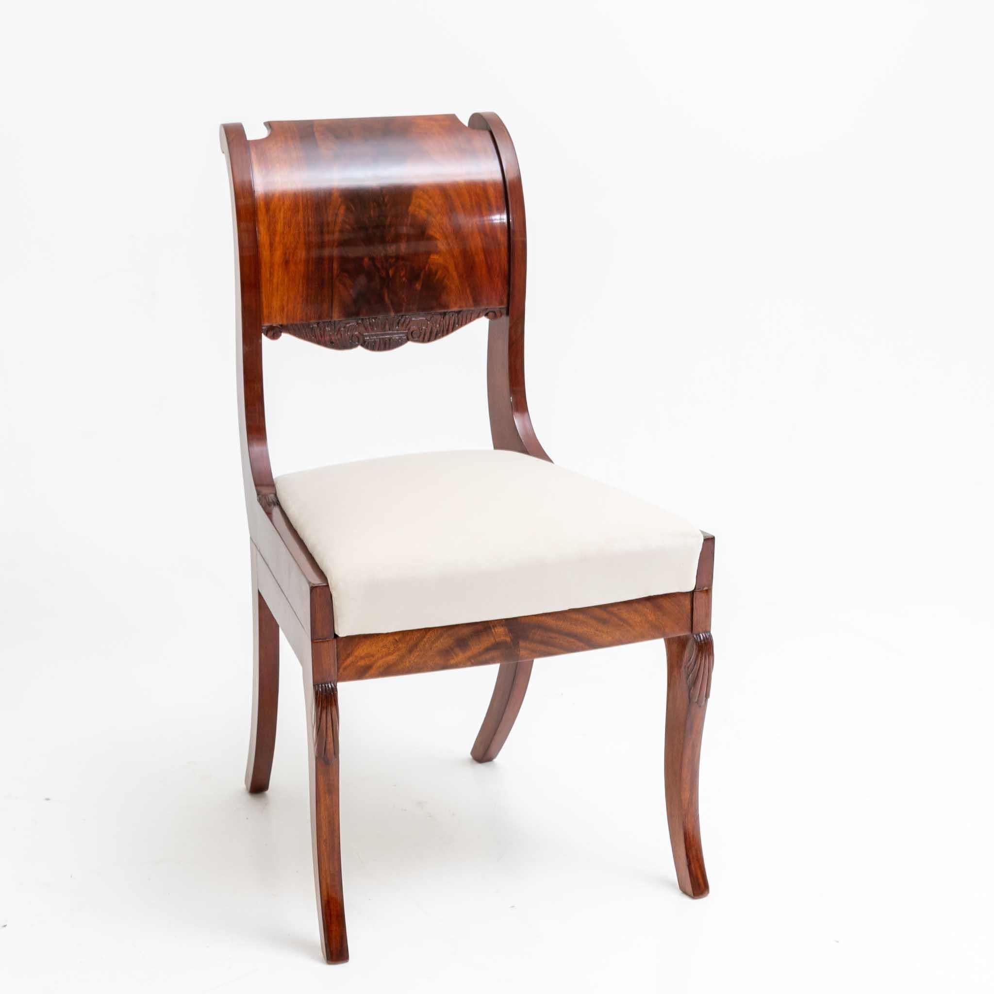 Pair of chairs with mahogany veneered frame and curved, slightly convex backs. The seats are newly covered with a white fabric. The chairs have been restored and hand polished.
