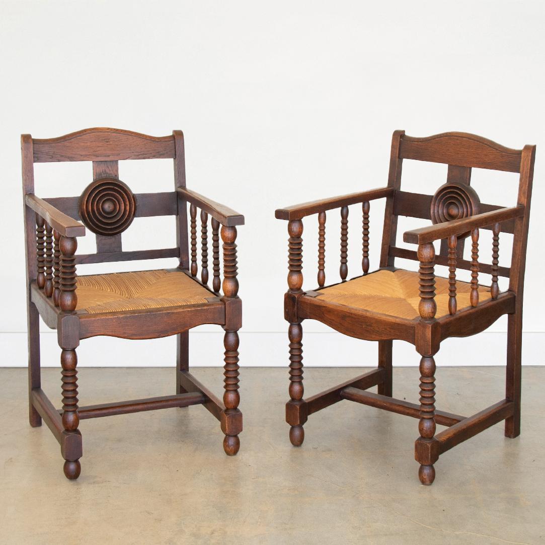 Great pair of carved wood armchairs by Charles Dudouyt from France, 1940's. Beautiful circular carved wood back and woven seat. Intricate carved wood detail on arms, legs, and wood frame with dark stain. Sold as a pair.