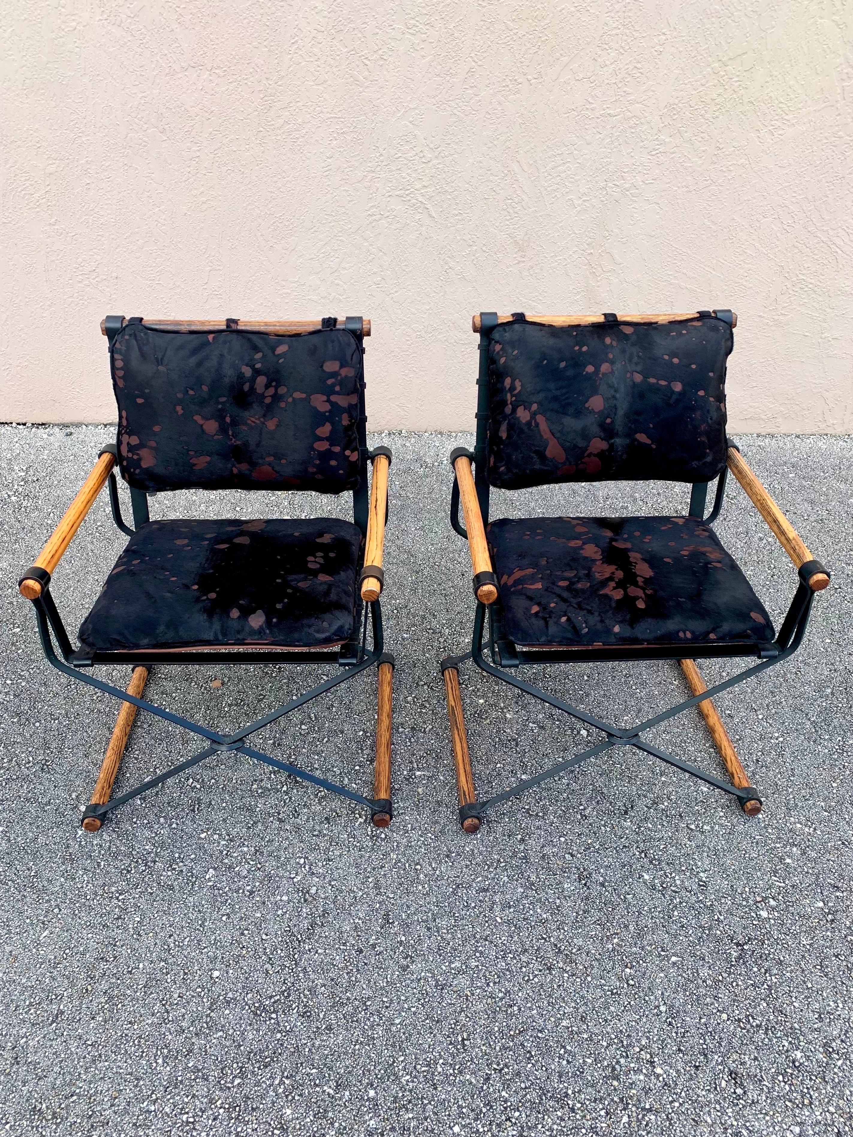 A pair of wrought iron and oak X frame chairs with cushions in the casual tradition by Californian Cleo Baldon for Terra Furniture, American, Circa 1970. 

Freshly upholstered in a beautiful black and brown hide on leather that beautifully