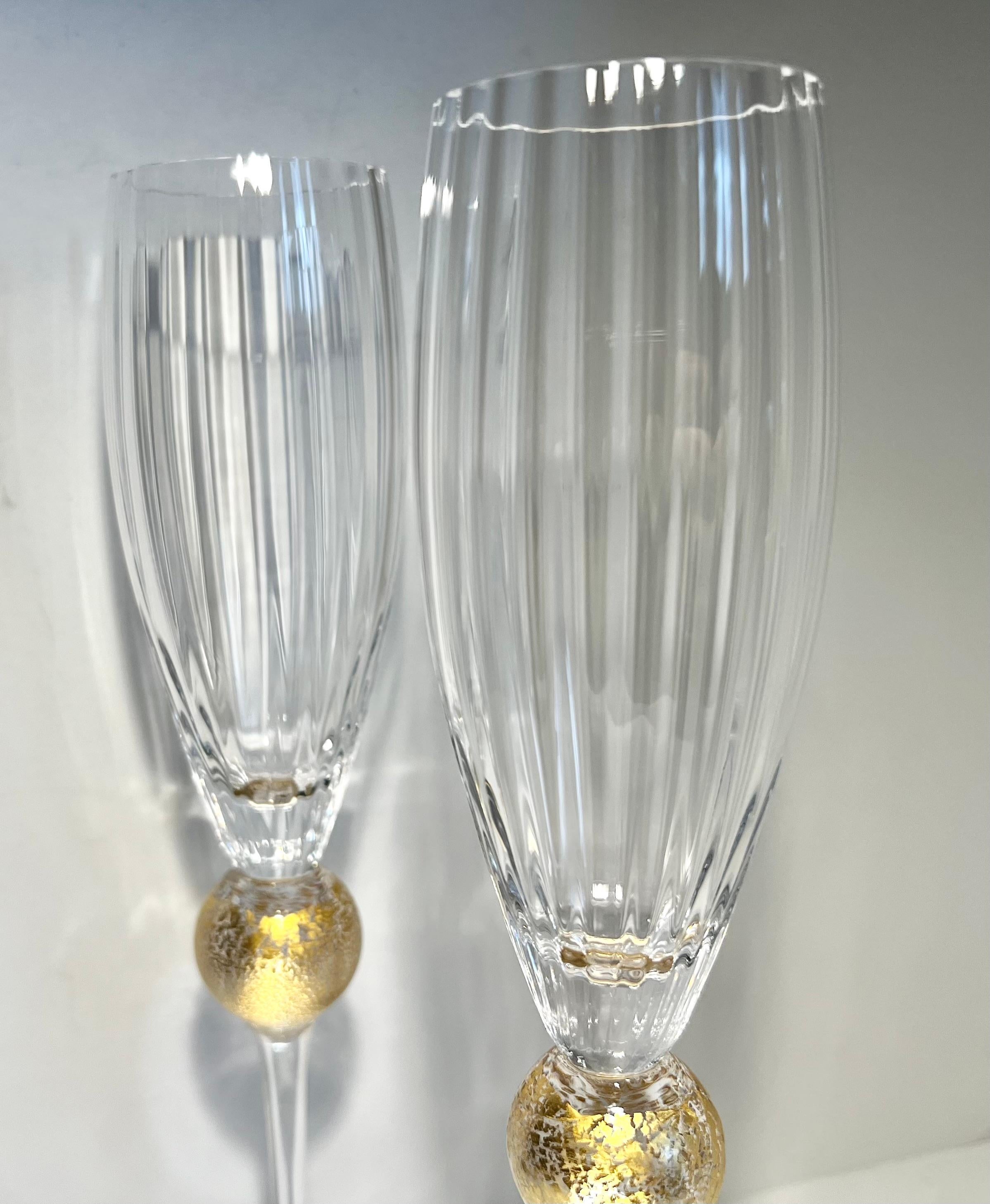 This pair of champagne flutes are by Union Street Glass part of the “Manhattan Collection”.  Each piece is handcrafted and unique. The clear glass optic bowl rests on a 24 carat leafed ball. The bowl rim is cut and polished. The foot is signed on