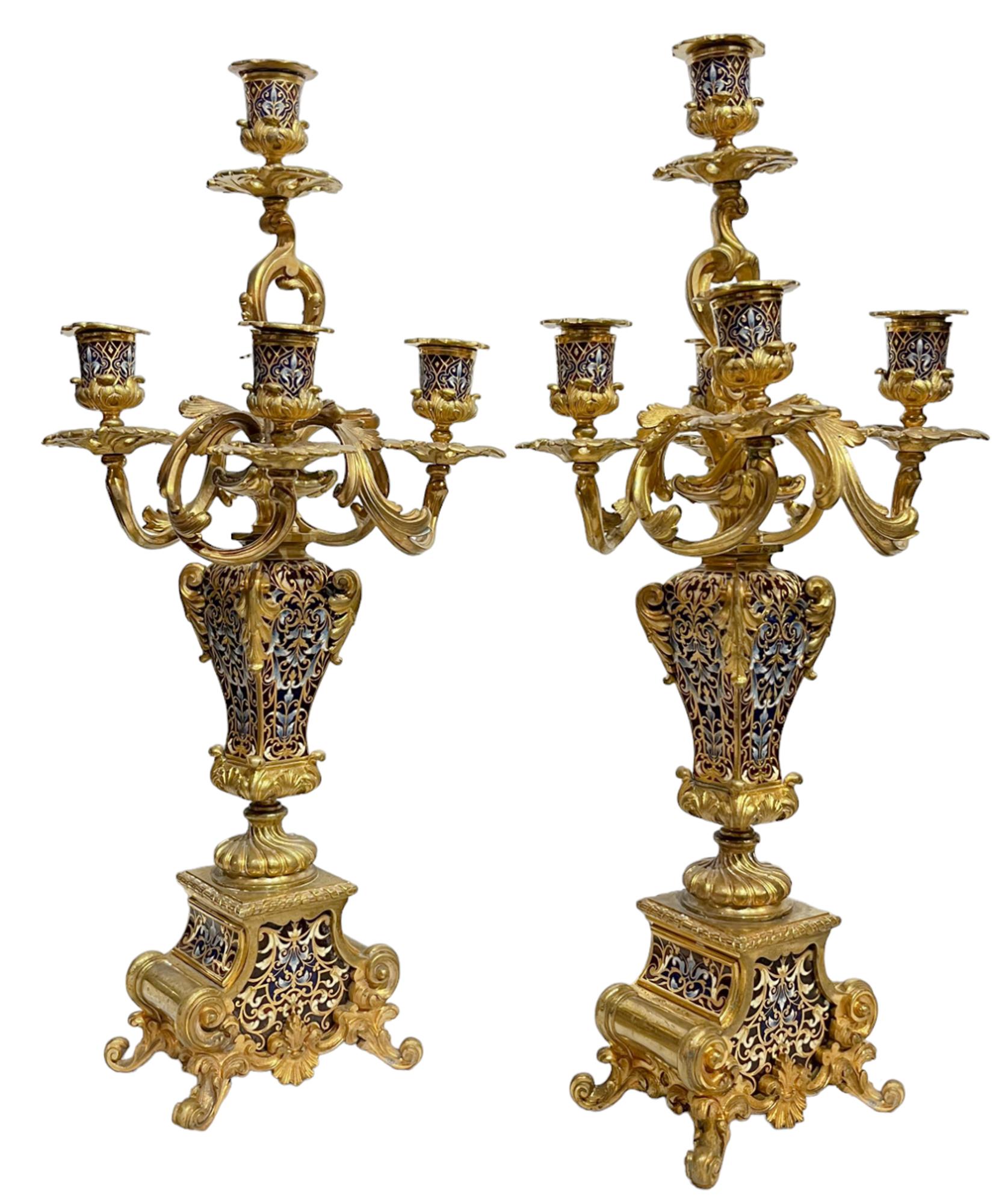 Pair of Champlevé and Gilt-bronze Five-light Candelabras

polychrome enameled and with scrolled foliate arms and candle nozzles atop square vasiform supports set on a scrolled base,

