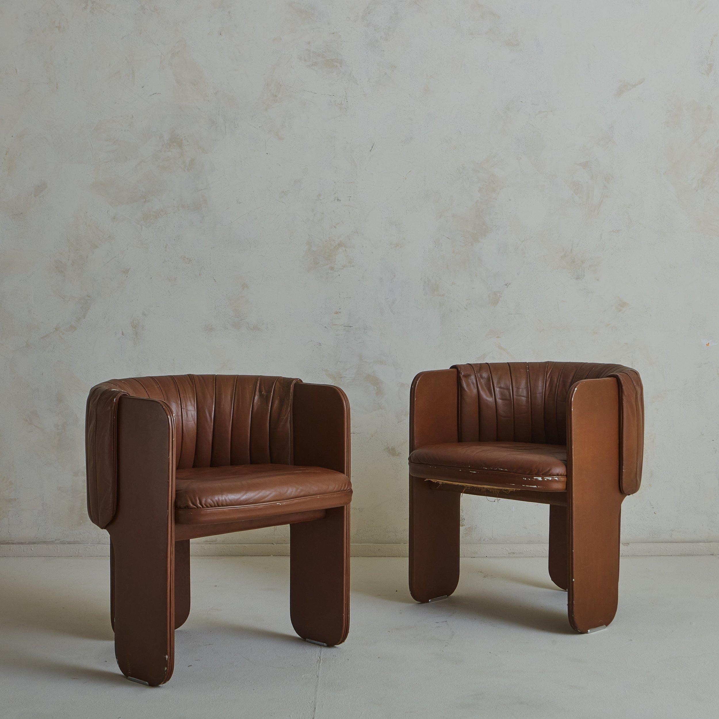 A pair of vegan leather accent chairs by Luigi Massoni for Poltrona Frau, Italy 1980s. These rare three-legged chairs feature elegant curvature and make the most of negative space, offering a remarkable perspective from every angle. We love the