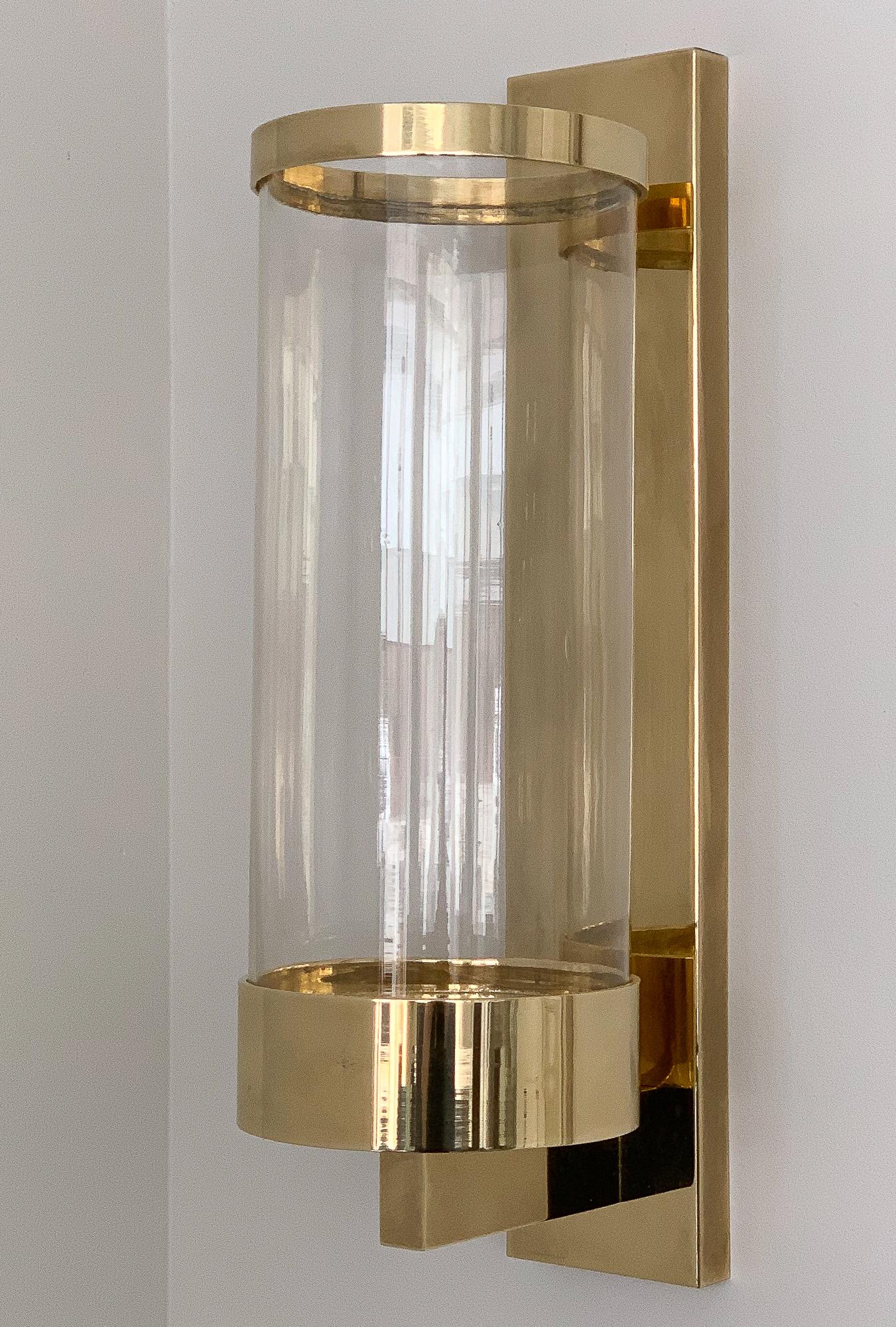 Pair of modern brass and glass candle wall sconces by Chapman Lighting, circa 1978. Polished solid brass and clear hand blown glass hurricane shades with brass rimmed tops. Graduated base to fit a variety of candle sizes. Original label on each