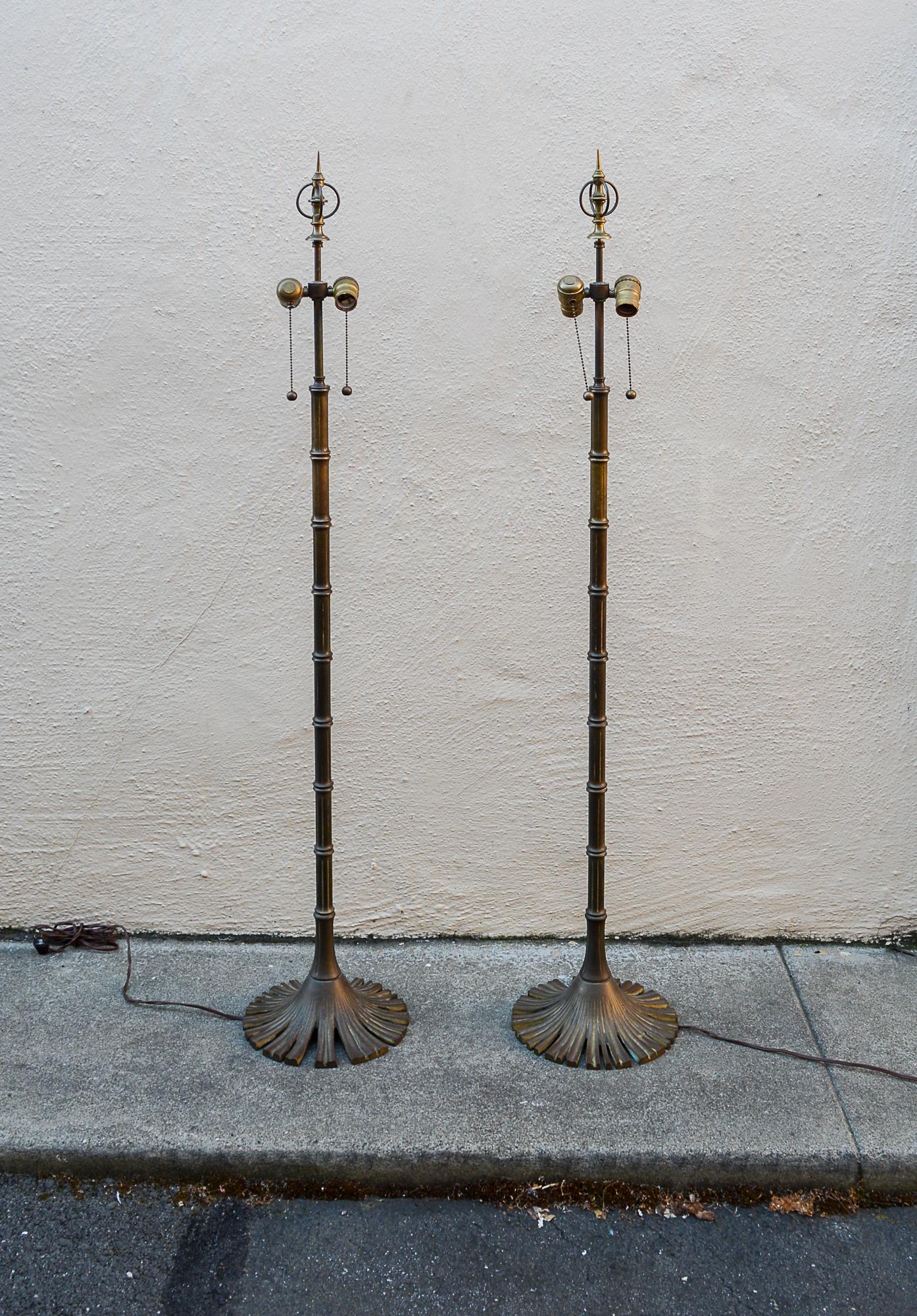 Pair of faux bamboo floor lamps made by Chapman Manufacturing. These have the original finials. The height given is to the top of the finial. The sockets are 45 inches tall. The lamps have developed a nice patina over time.