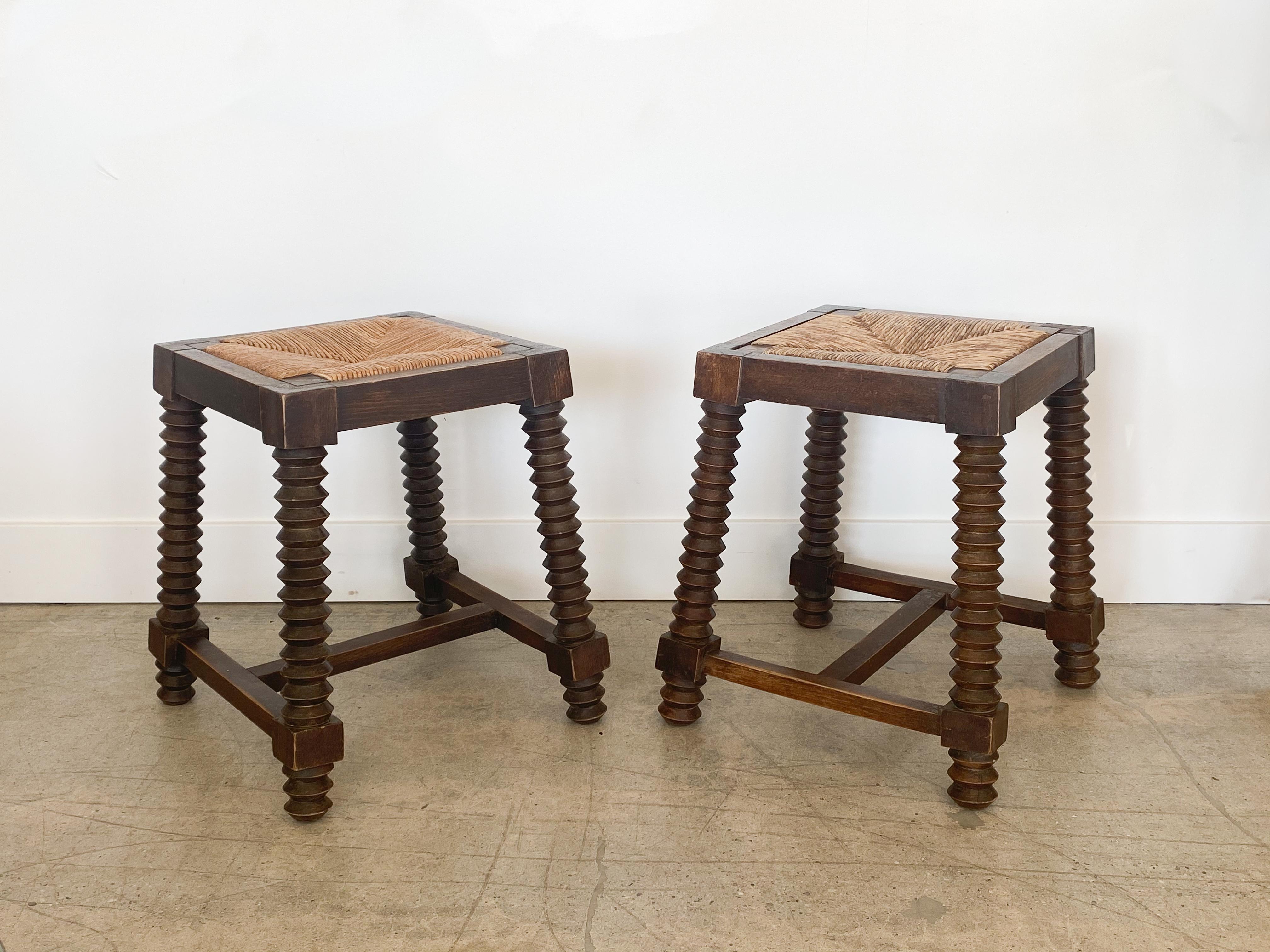 Pair of French 1940s stools by Charles Dudouyt. Dark carved wood legs with original finish and original woven rush seats.