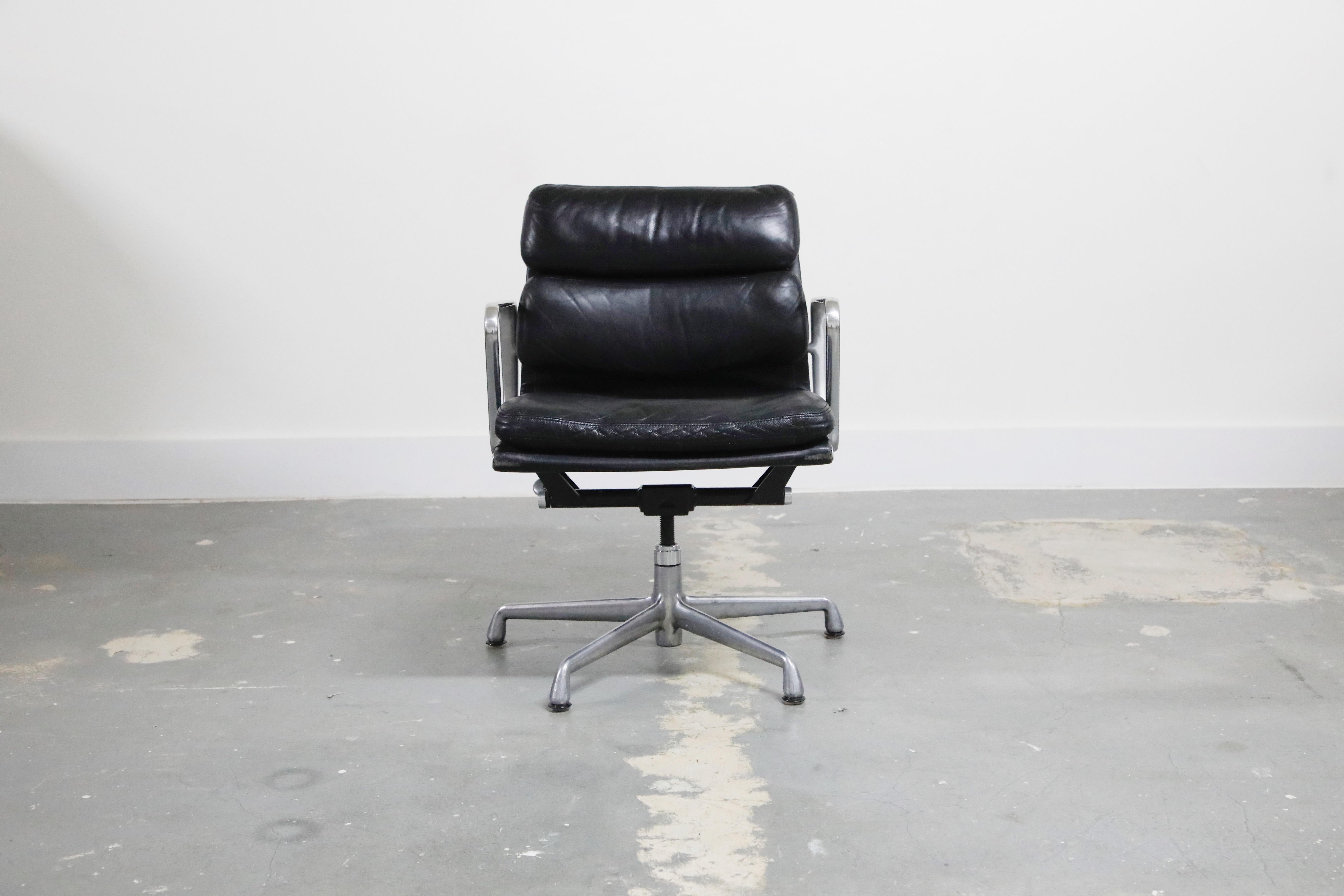 A collectible and sought after pair of leather 'Soft Pad' Management chairs from the Aluminum Group line, designed by Charles and Ray Eames for Herman Miller. Featuring its original black leather over five-star aluminum base. Signed underneath with