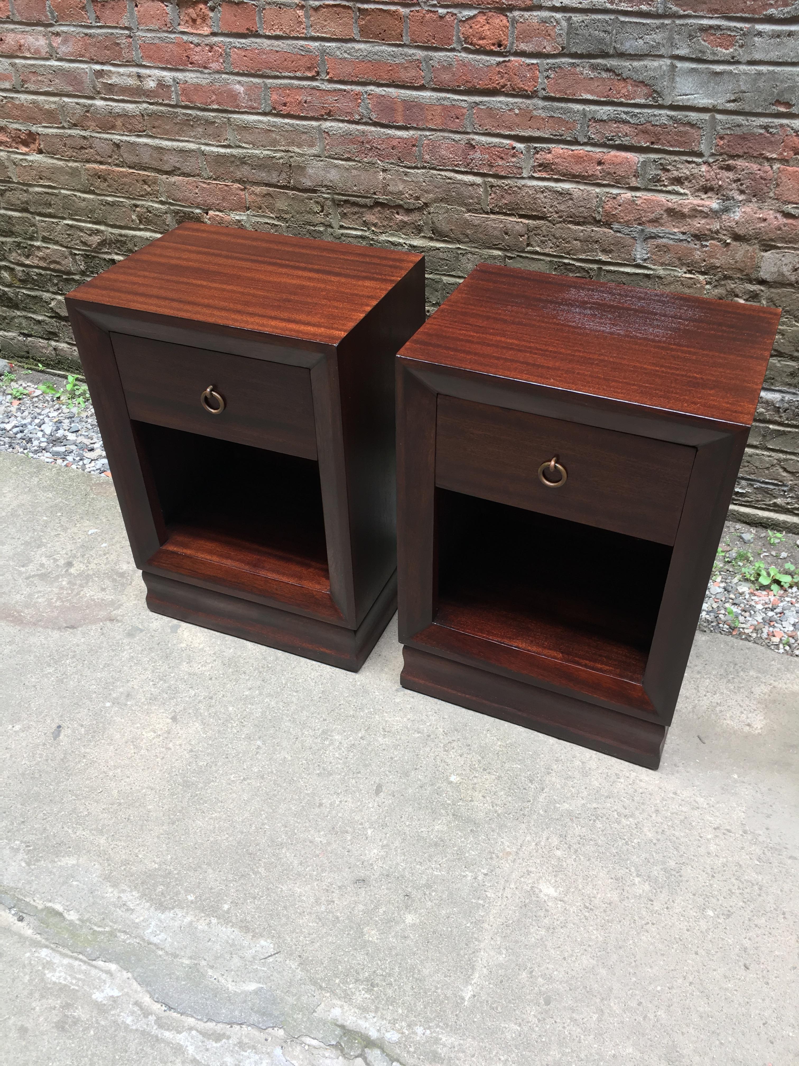 Excellent pair of mahogany with bronze ring pull end tables. The end tables feature solid bronze ring pulls, shaped plinth bases, figured mahogany veneers and bevel edge fronts. Signed in the drawer with a burn in mark, Decorator's Row Creation,