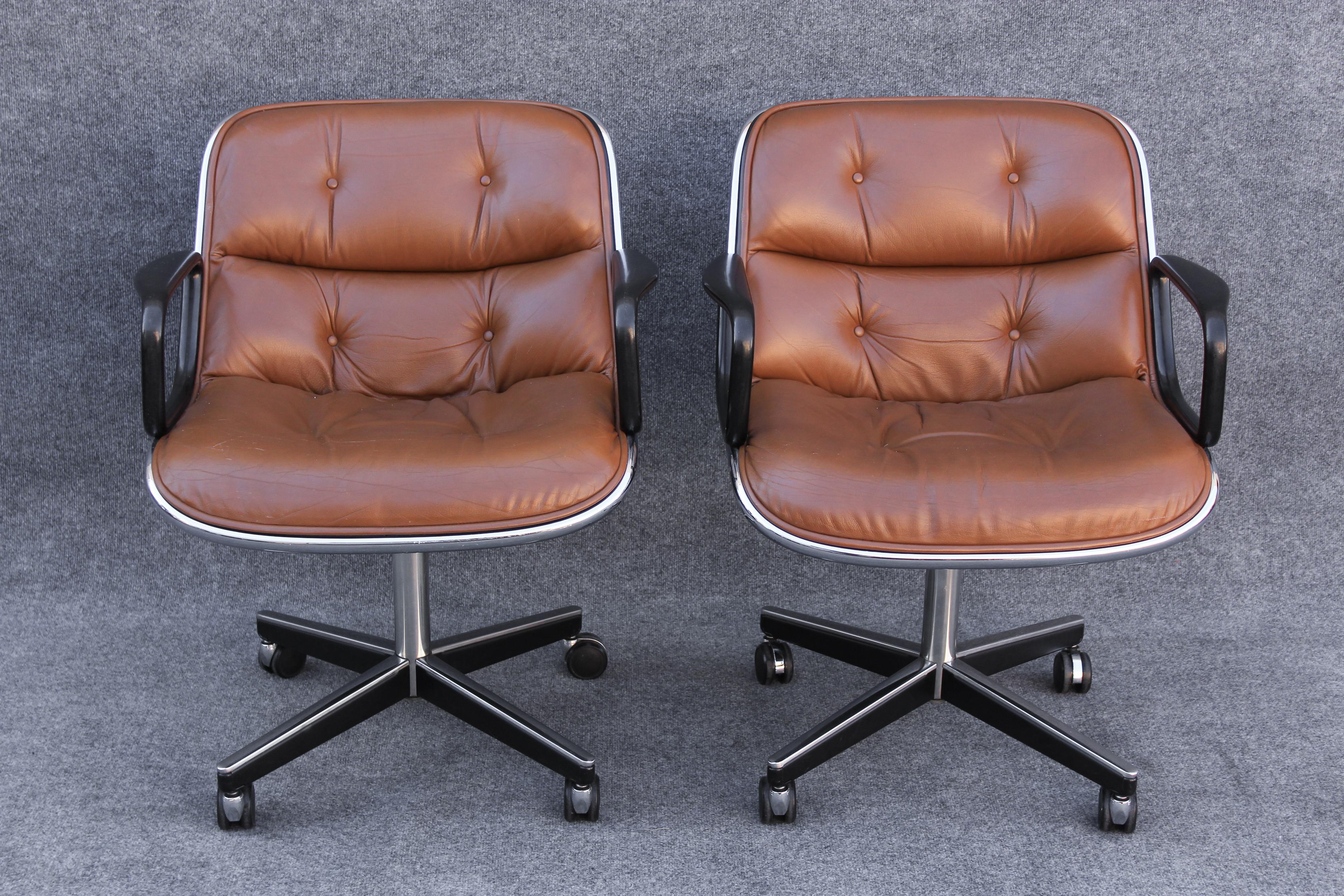 Produced by Knoll, these chairs were designed by Charles Pollock. Dated by the address on the label, these were made in the 1960s. This pair features dark brown leather and a chromed steel exterior, set on a 4 star base of rectangular chrome and